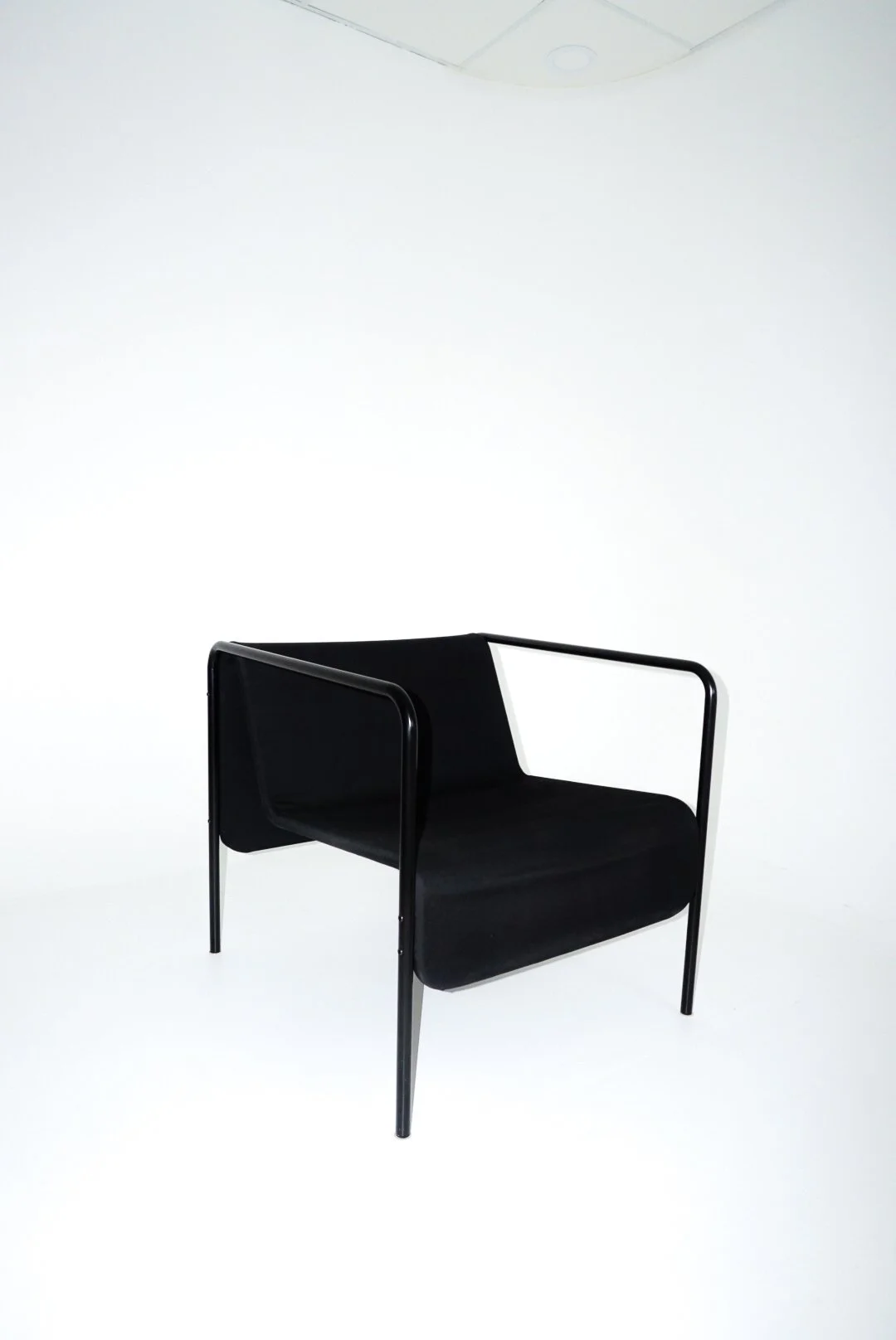 A black armchair with a modern design, featuring a curved back and armrests, set against a plain white background.
