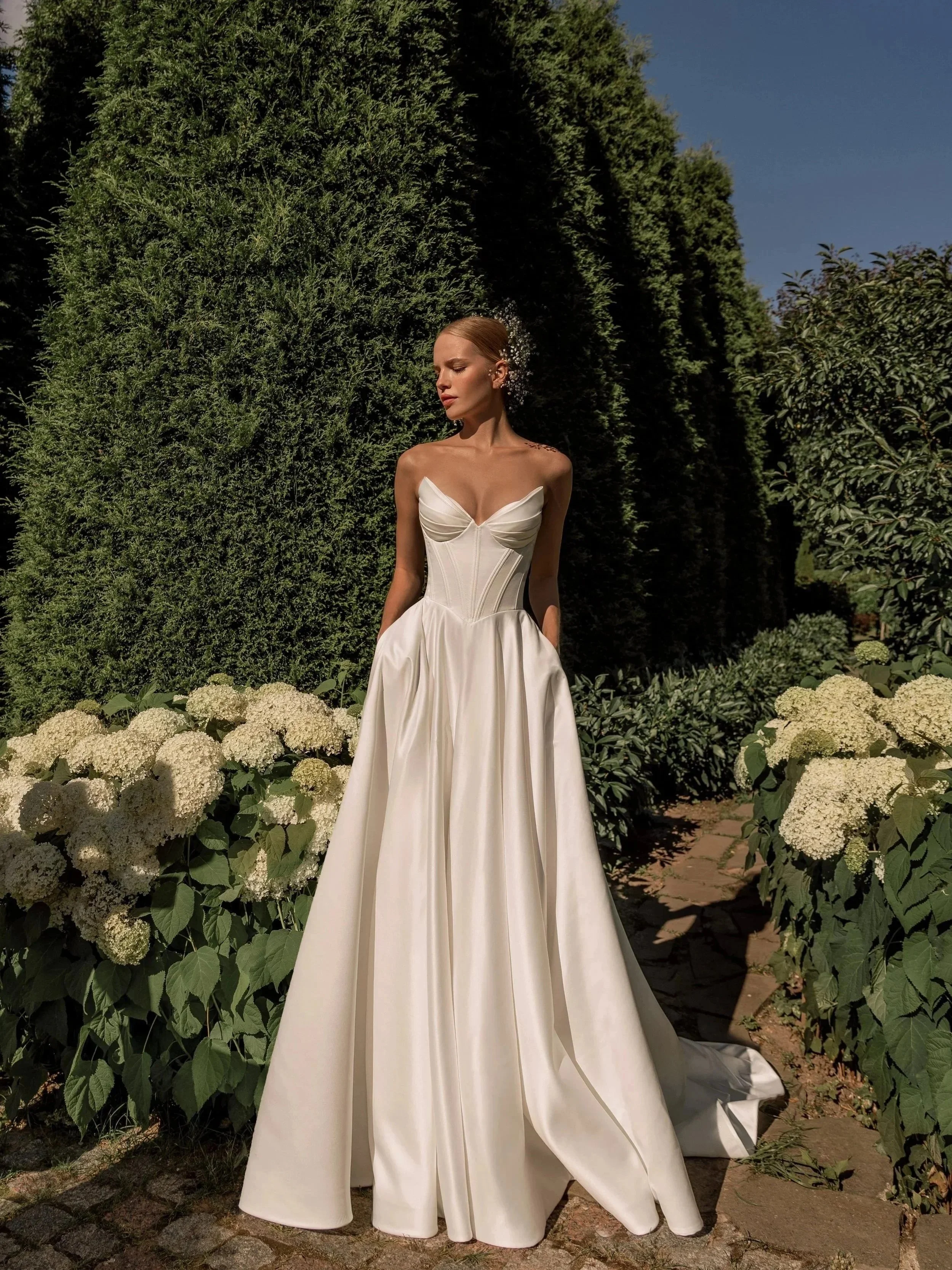 Bride in the Sanlar gown by Tatiana Kaplun, a structured satin A-line with a peaked neckline and corset back