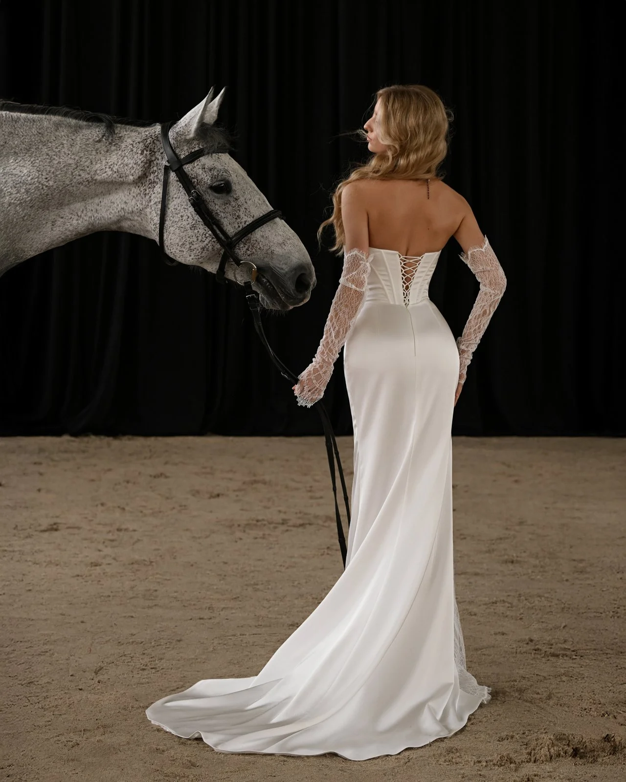 Viil satin bridal gown with basque waist, lace sleeves, and slit detail flowing movement shot full back view