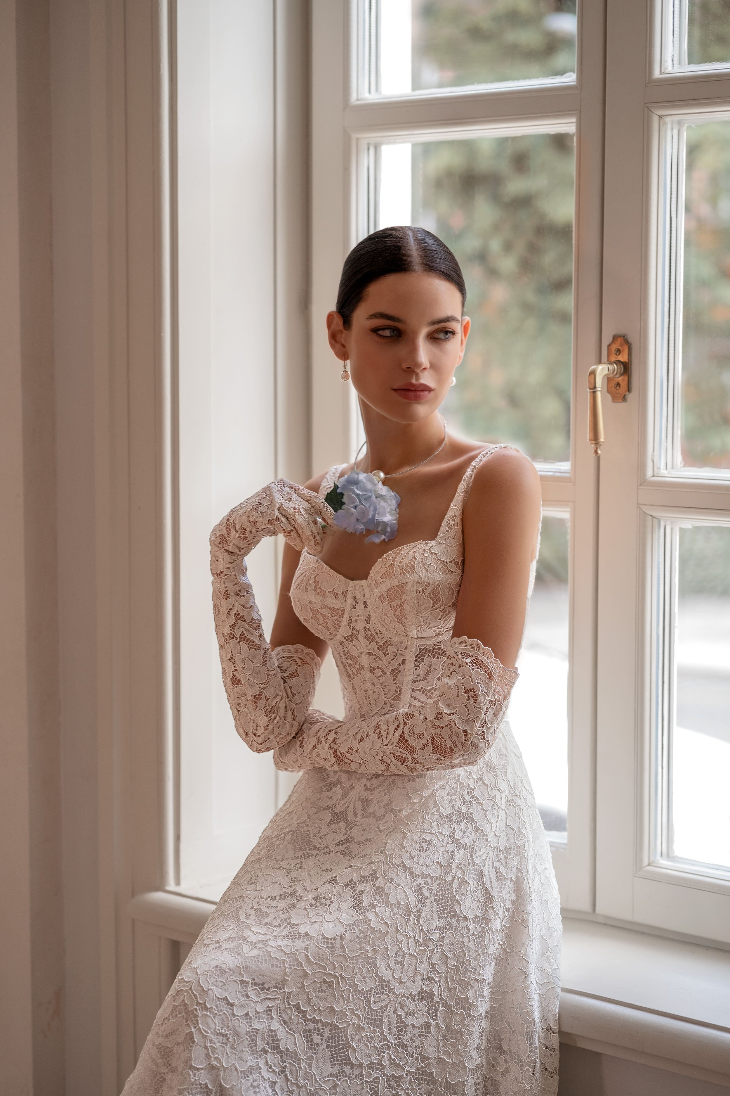 Detailed view showing the intricate lace craftsmanship of the Kapris gown and the matching gloves that complete this romantic, one-of-a-kind bridal look.