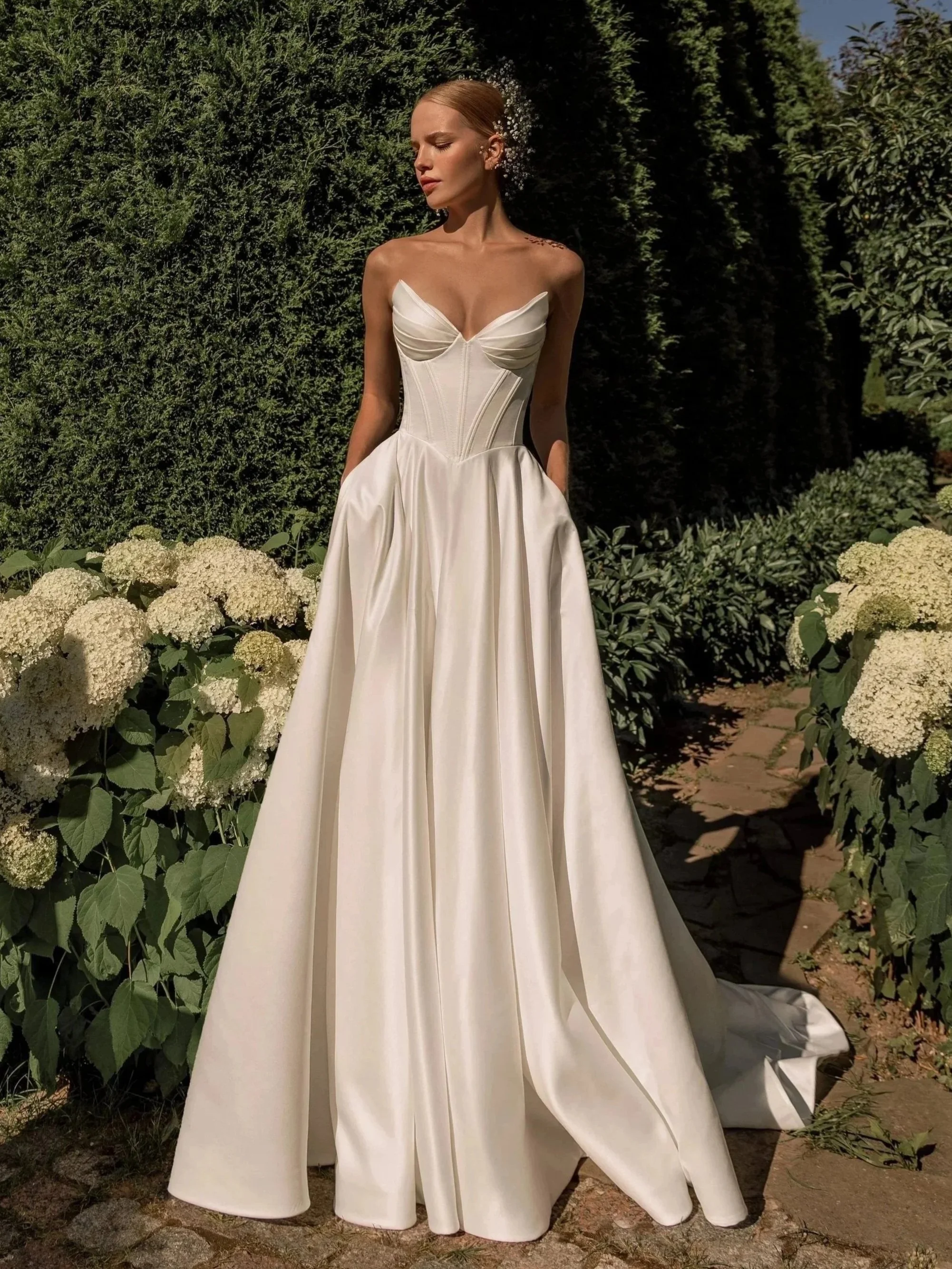 Minimalist white wedding dress Sanlar by Tatiana Kaplun, basque waist with an A-line skirt and a trapless cateye neckline.