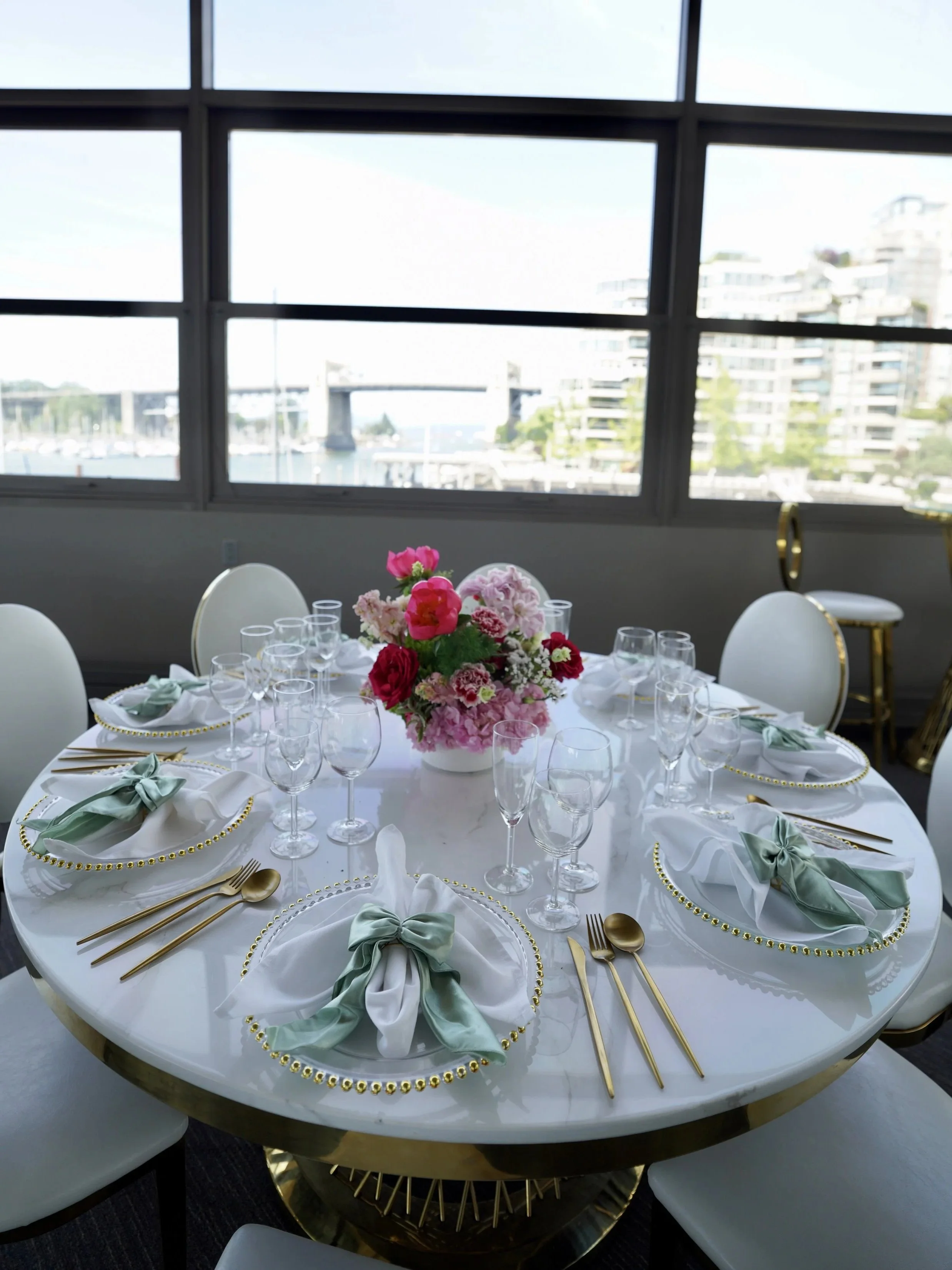 Elegant wedding welcome dinner table setting with sage napkins, gold cutlery, and a pink floral centrepiece