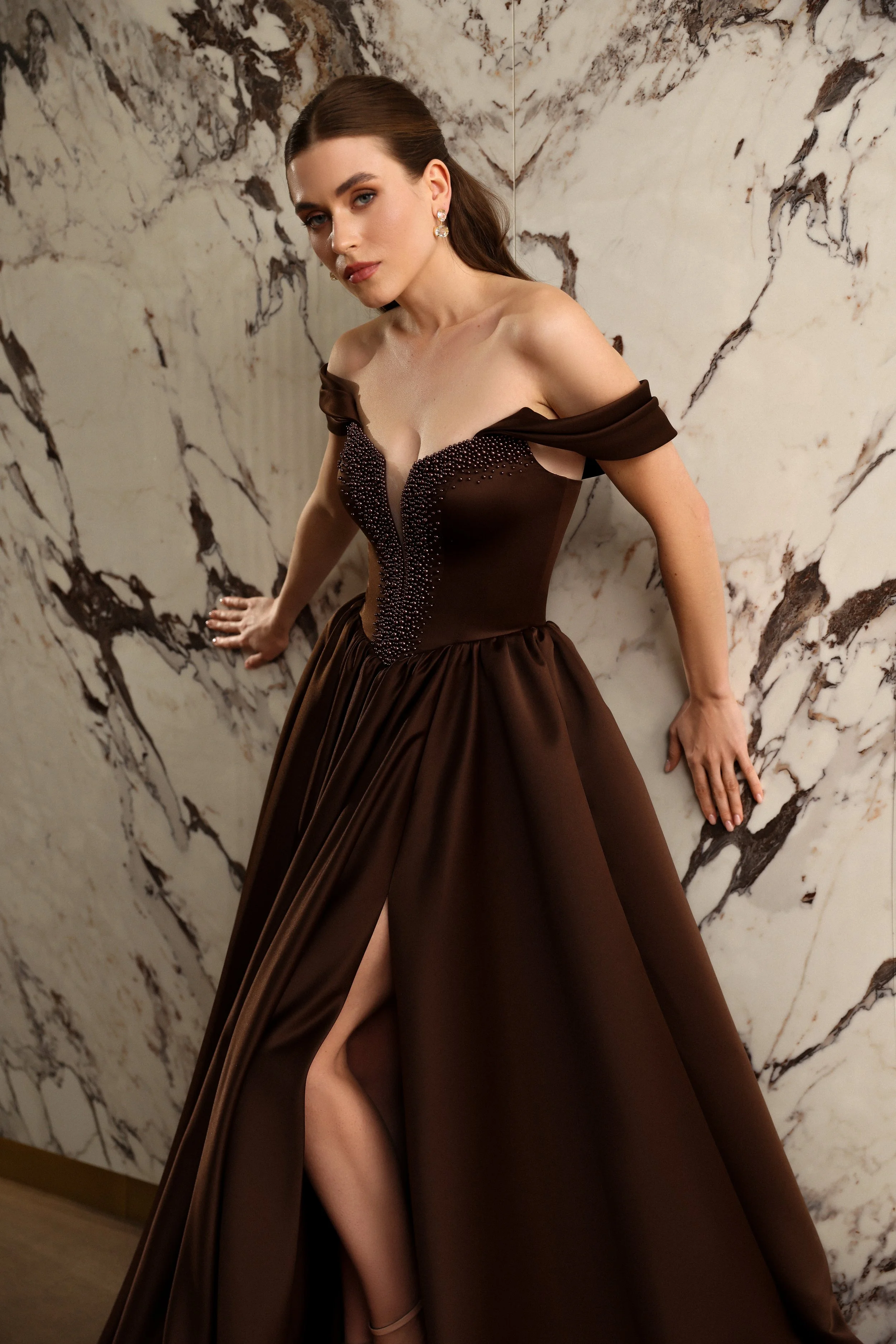 Close view of a luxurious brown satin prom dress with off the shoulder sleeves and elegant basque waist.
