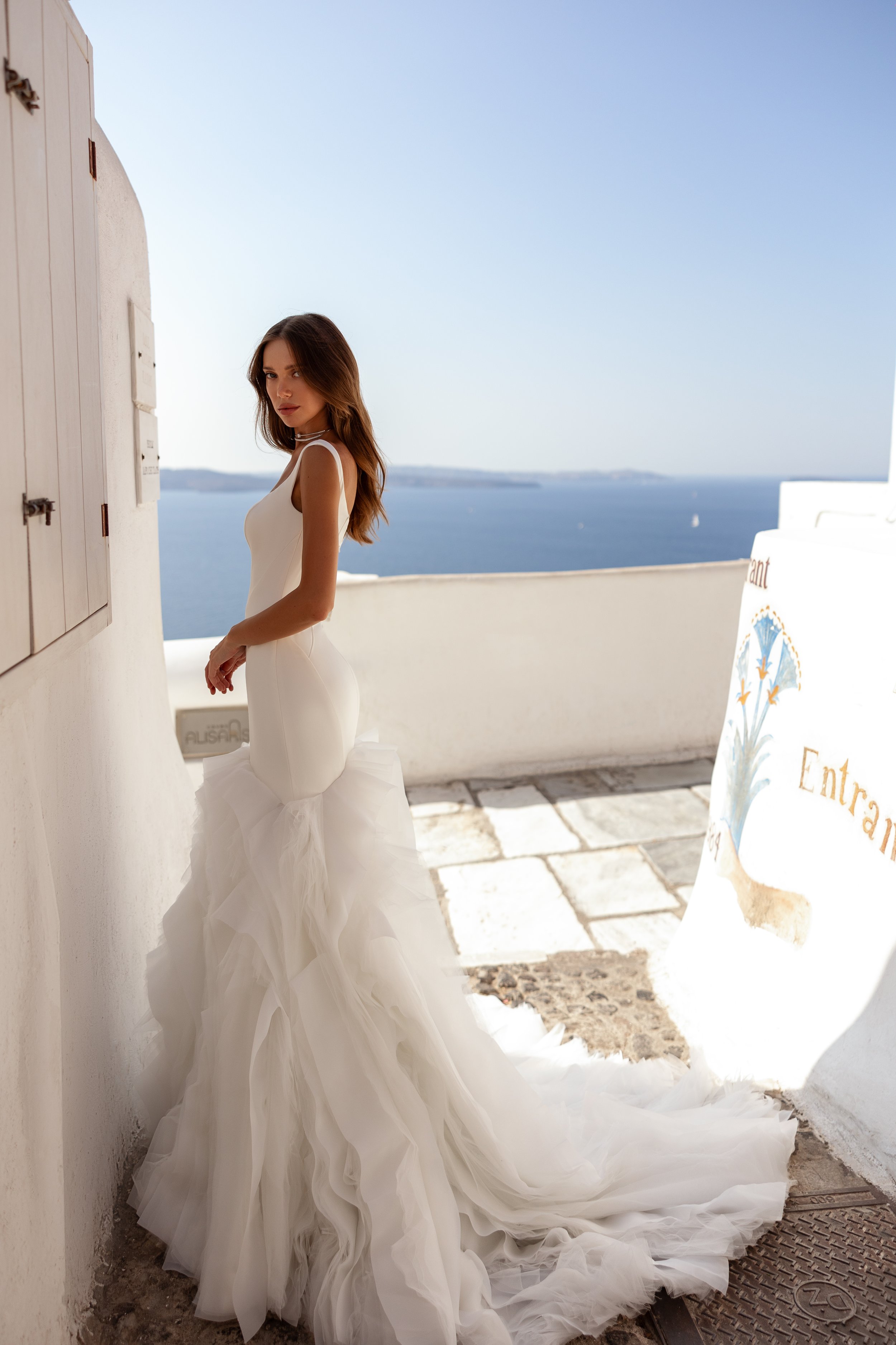 Side view of a fitted crepe trumpet wedding dress highlighting a sleek silhouette and ruffled skirt.