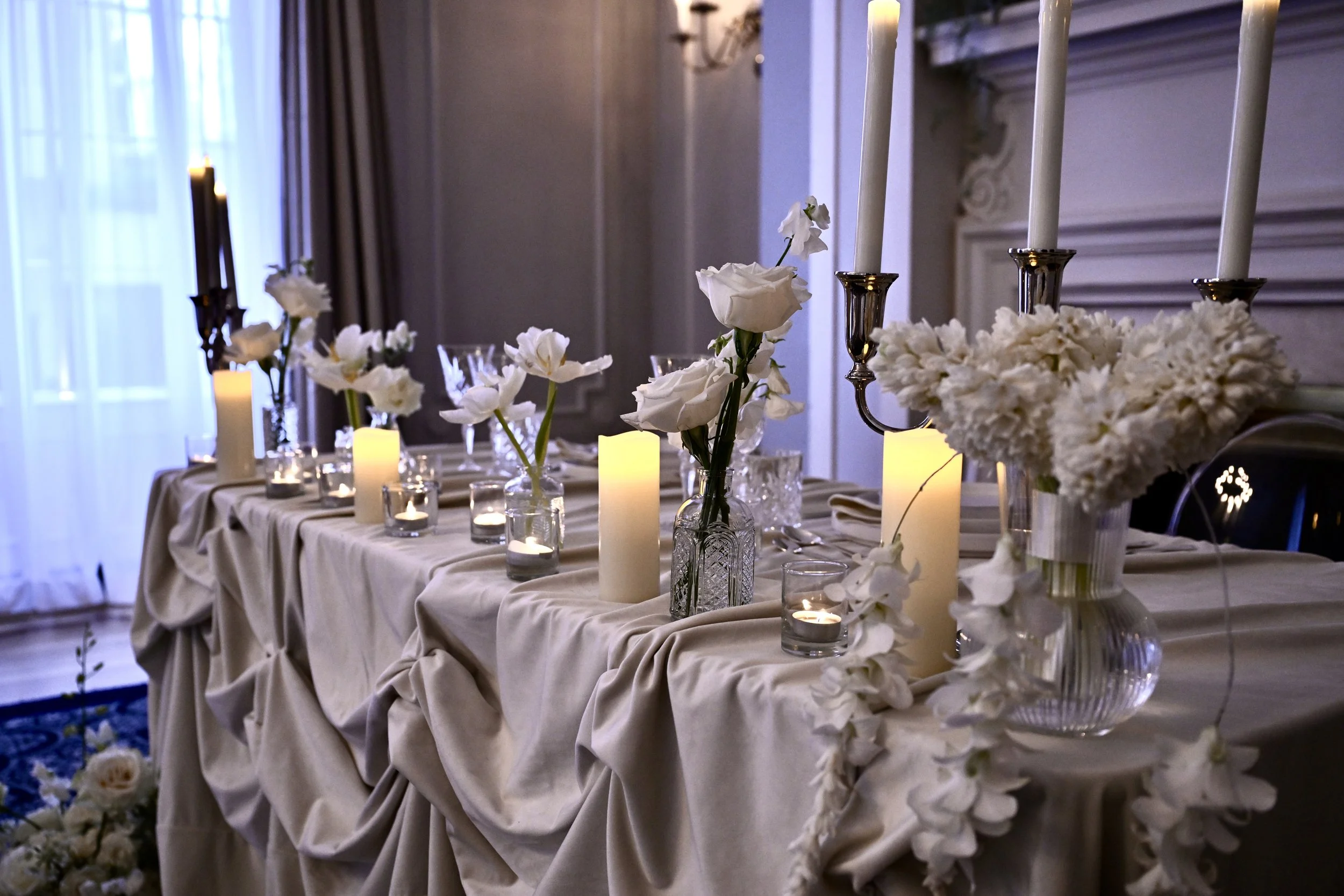 White-floral candlelit reception table with silver candelabra and draped linen at The Vancouver Club, a downtown heritage venue