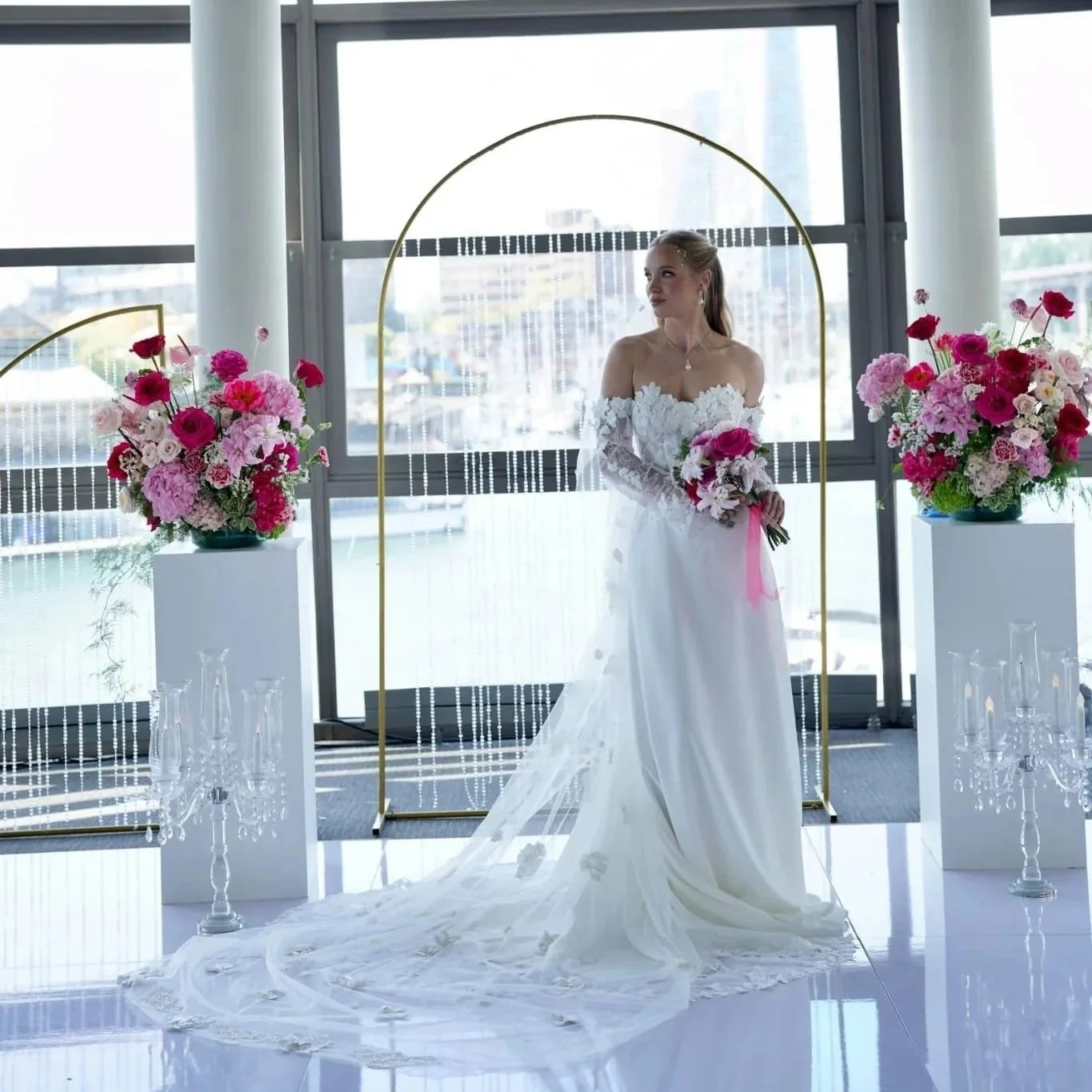 Mirella wedding gown by Aria with a veil and bouque on a white stage.