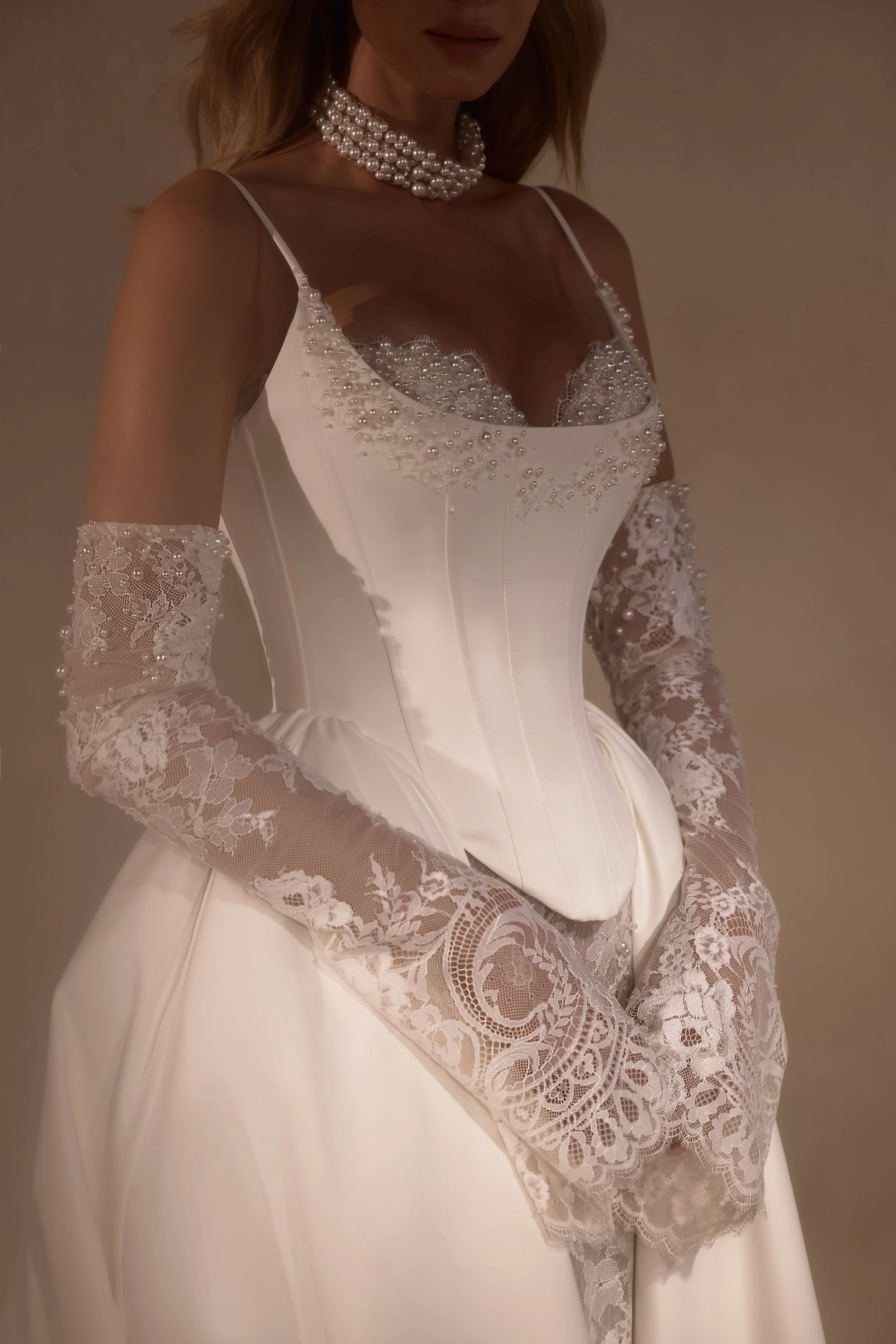 Smooth matte satin slip wedding dress with thin straps, lace and pearl embroidered bodice, and pleated train.