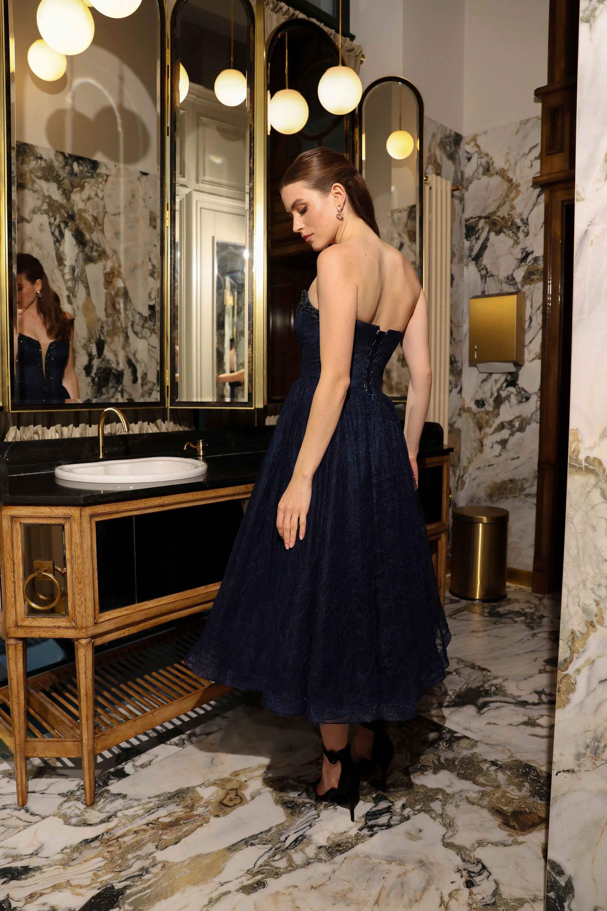 Back view of an elegant Chantilly lace tea length dress with intricate lace detailing and a fitted silhouette.
