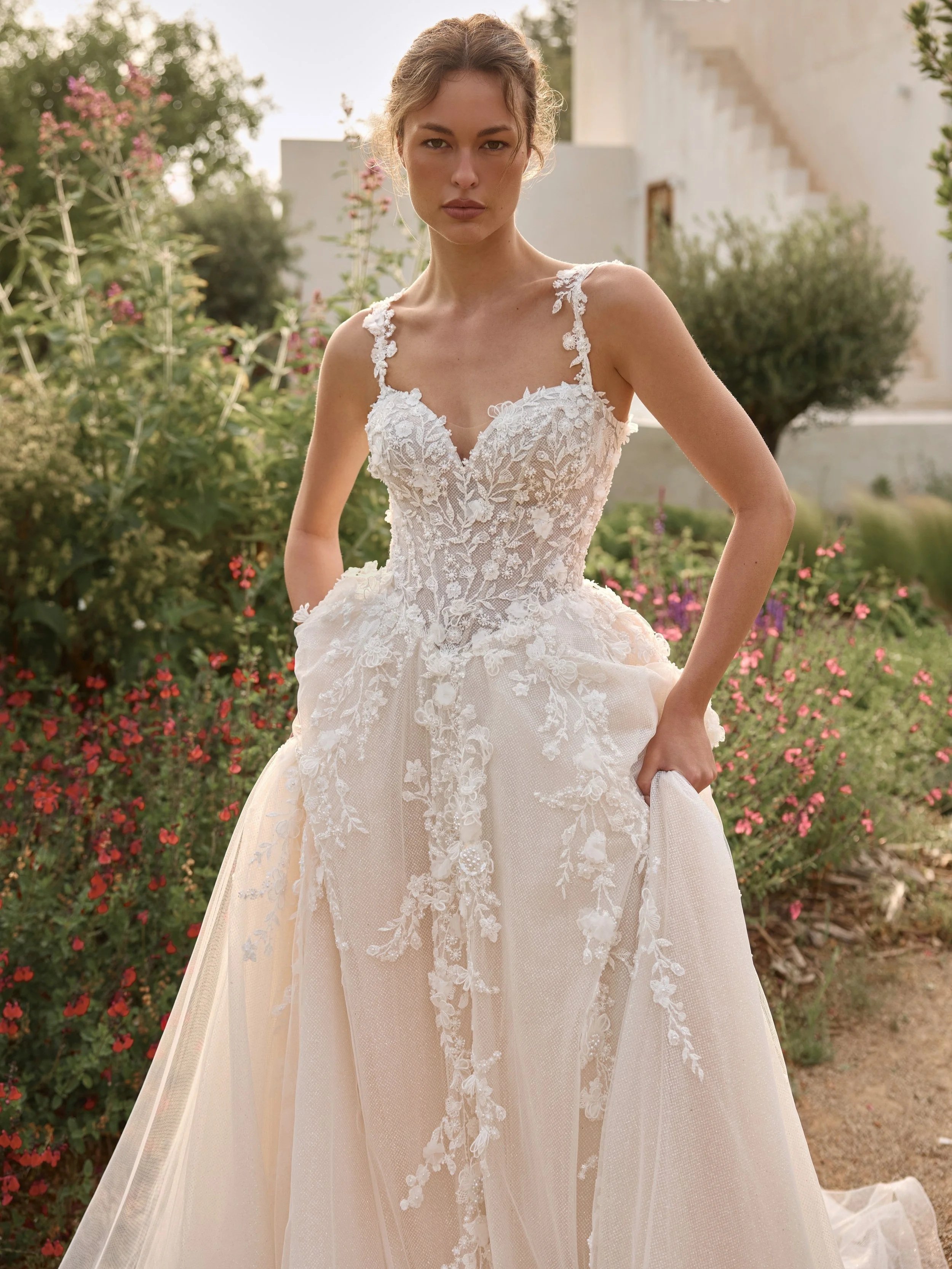 A bride in a wedding dress by Ari Villoso, Sweetheart neckline with straps, floral applique and an A-line skirt.
