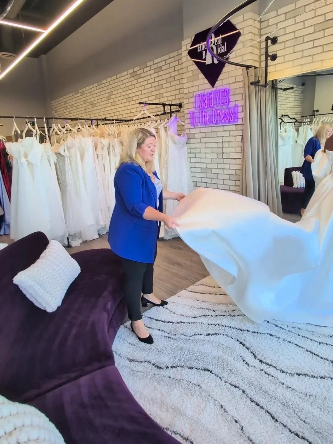 A bridal stylist adjusting the train on a dress at ethereal bridal boutique in port moody.