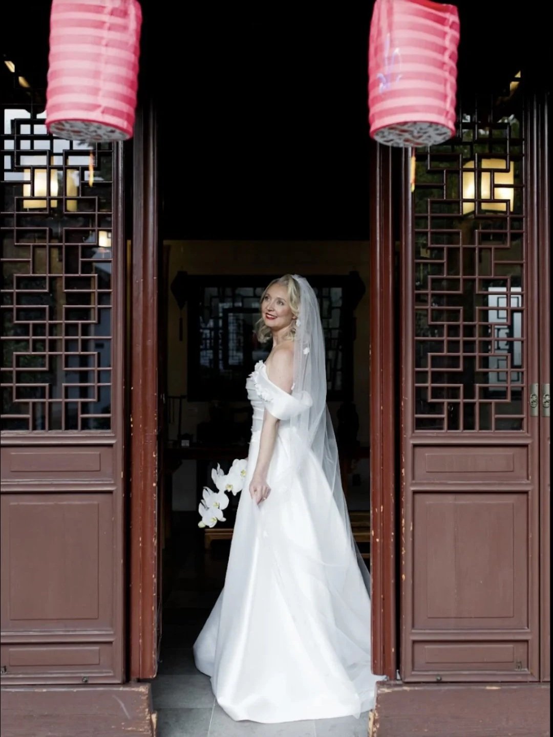 Real Bride in a wedding dress standing in a doorway.