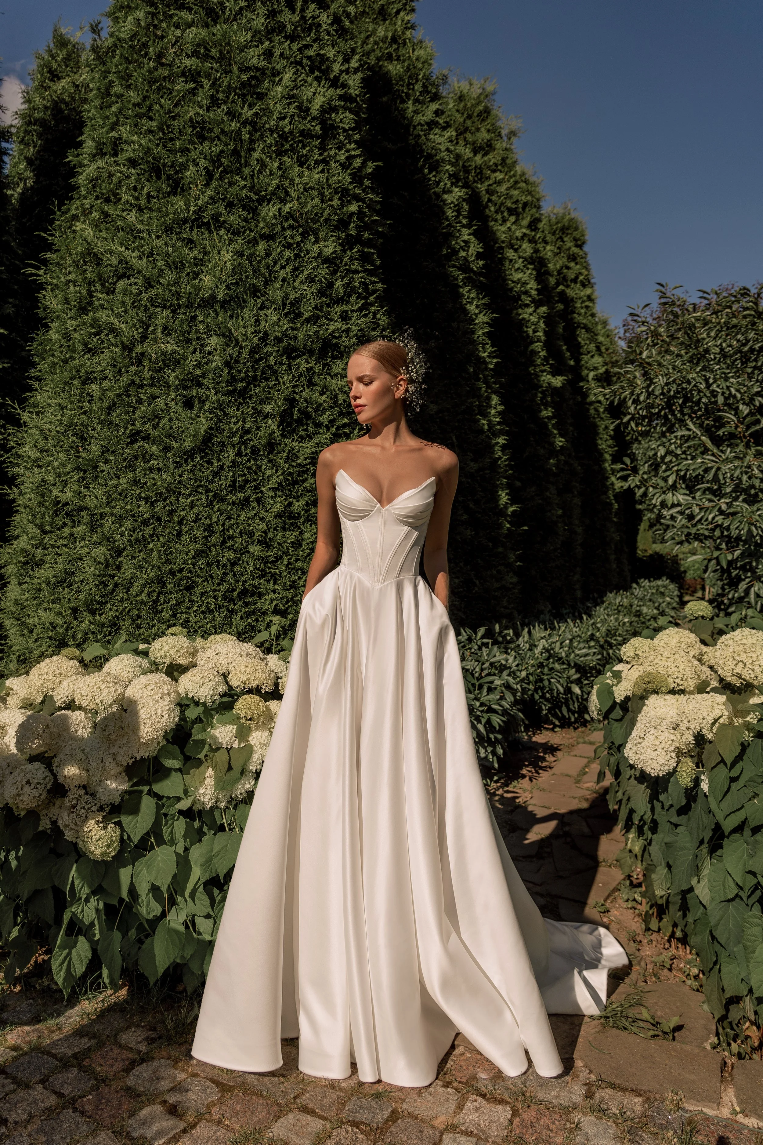 Front view of Sanlar A‑line wedding dress featuring a peaked neckline and structured satin bodice.