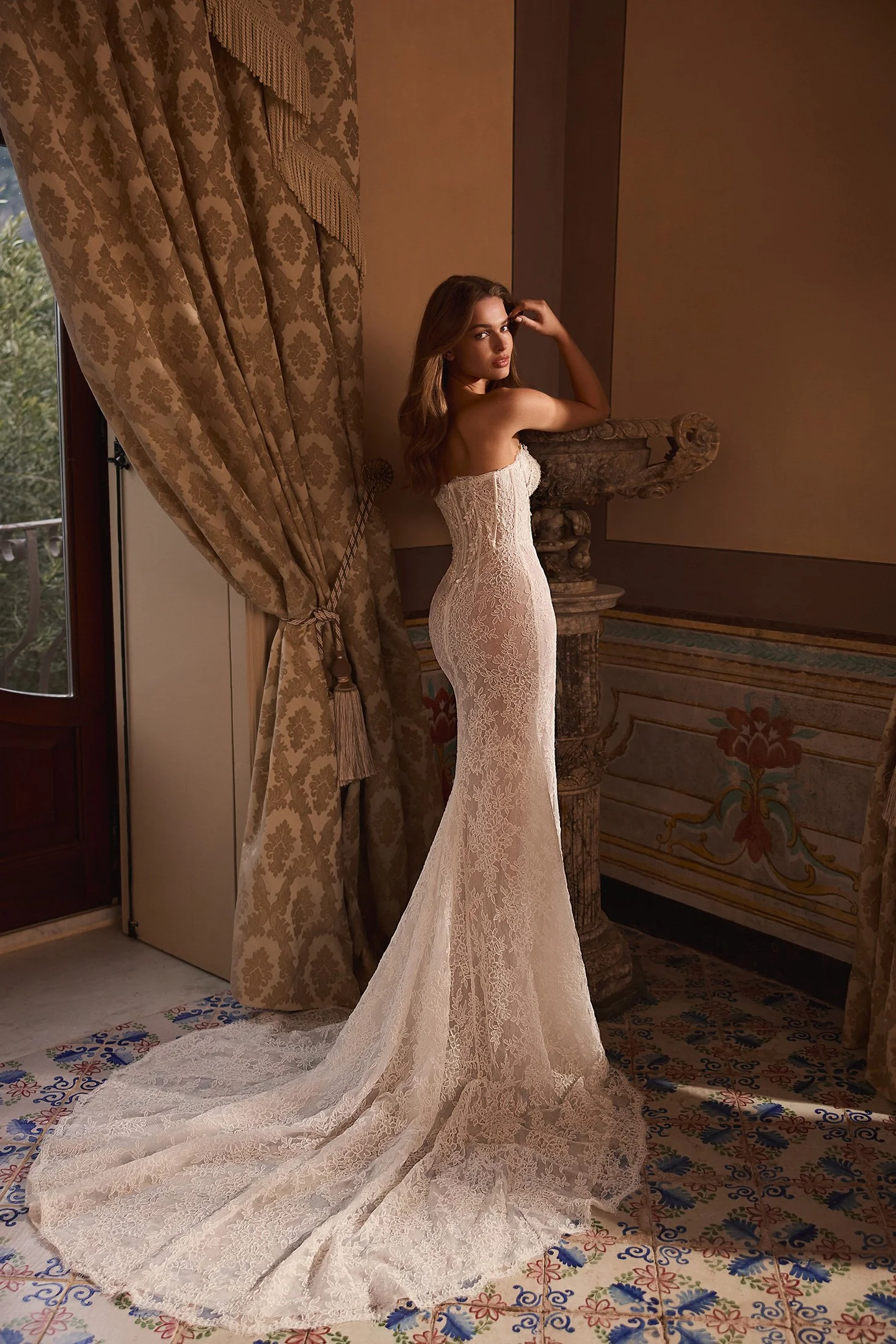 Elegant back view of the Siren gown highlighting the exposed boning, sculpted V-waistline, and detailed 3D lace appliqués for a dramatic bridal look.