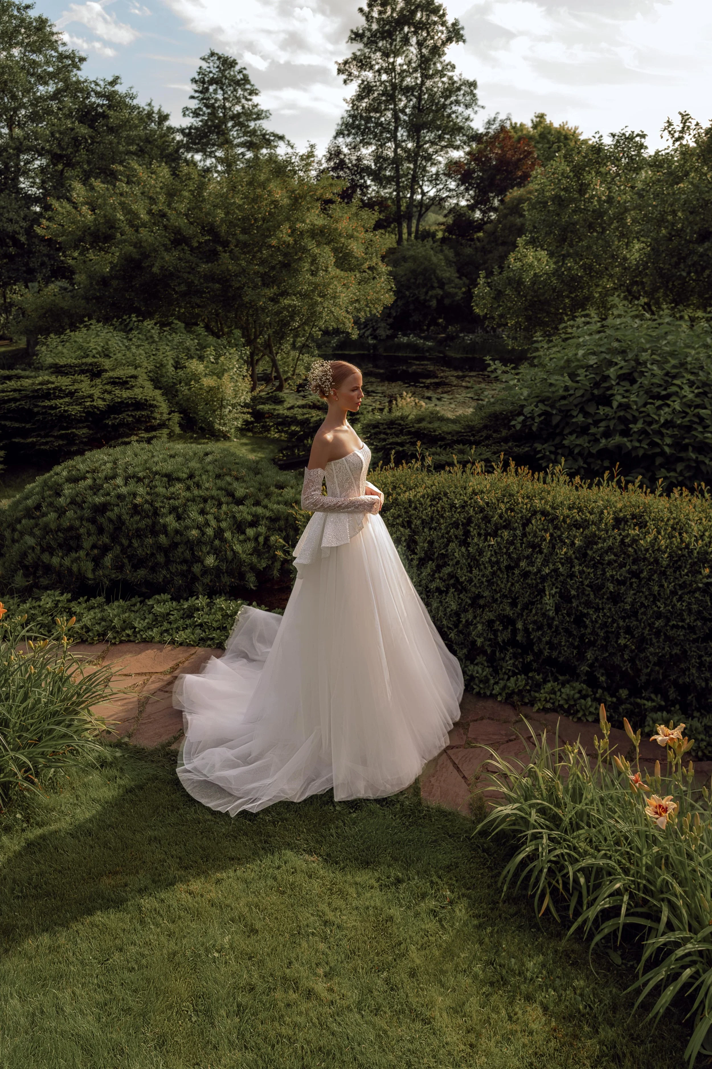 Side view of the Kaimana two-piece wedding dress, highlighting the peplum, sparkling lace corset, glittering sleeves, and flowing tulle skirt.