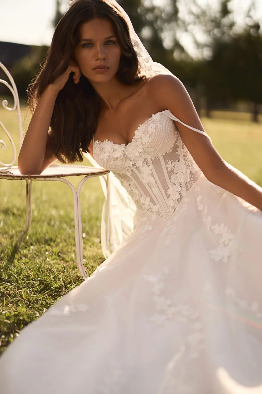 Close-up of Epine pointed bodice adorned with floral lace, three-dimensional flowers, pearls, crystals, and beads