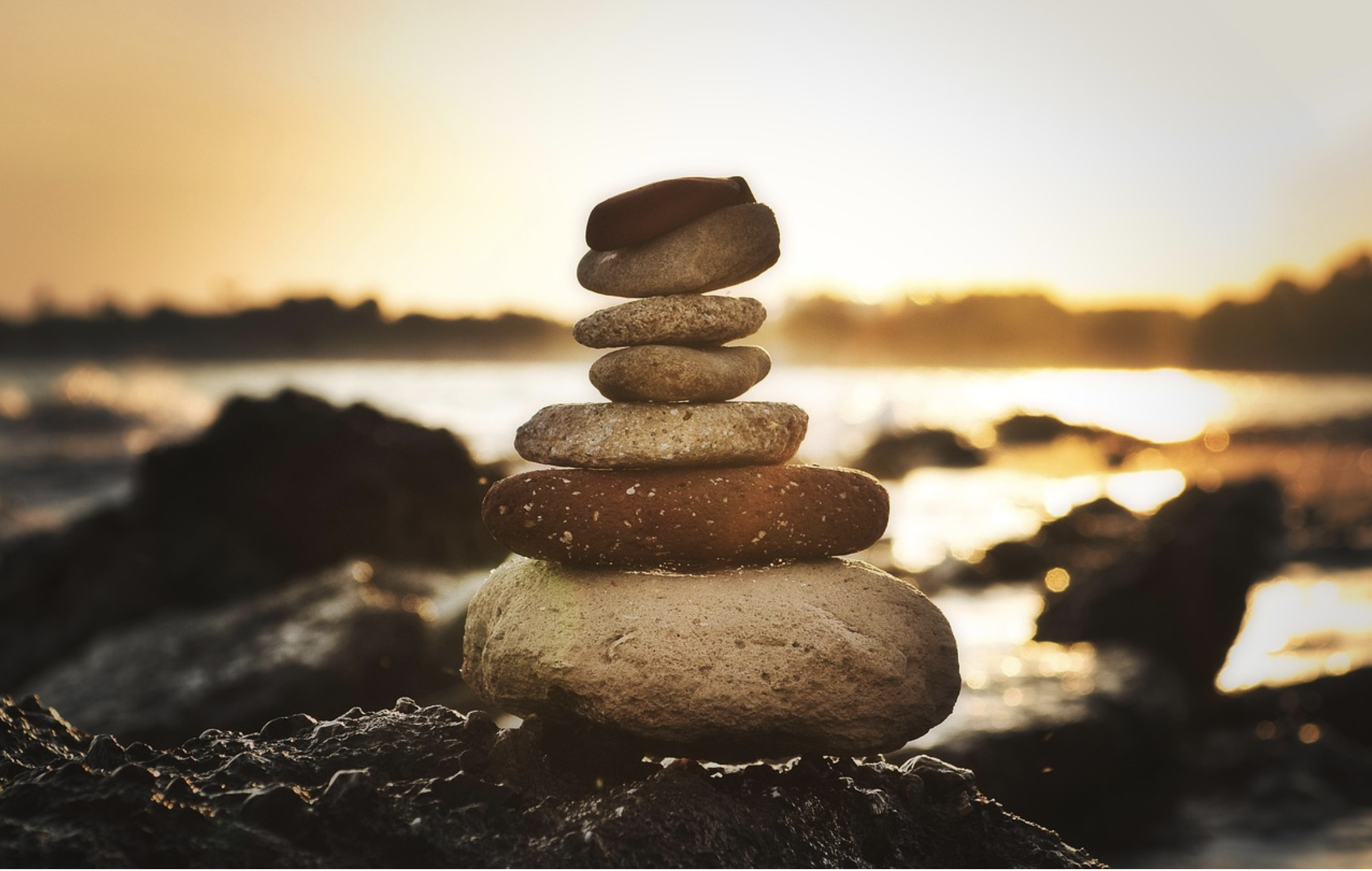 Rocks balanced and stack on each other in sunset light with the ocean in the background