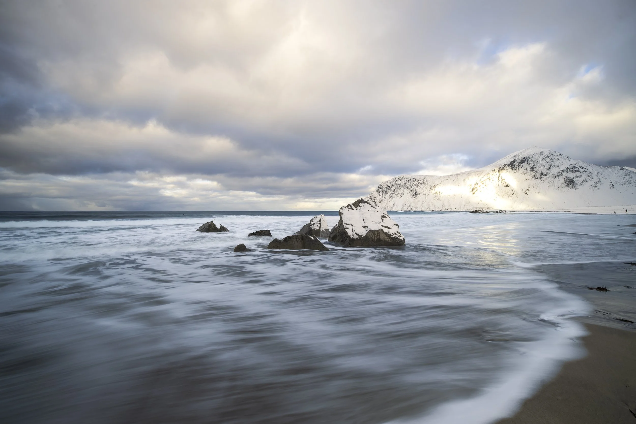 Flakstayoa, Lofoten, Norway 2026. I stepped out of the car instantly drawn to this beautiful scenery dominated by the 3 prominent rocks in gushing water and framed by the beautiful mountain in the background. 
Knowing the sandy beach would soon fill 