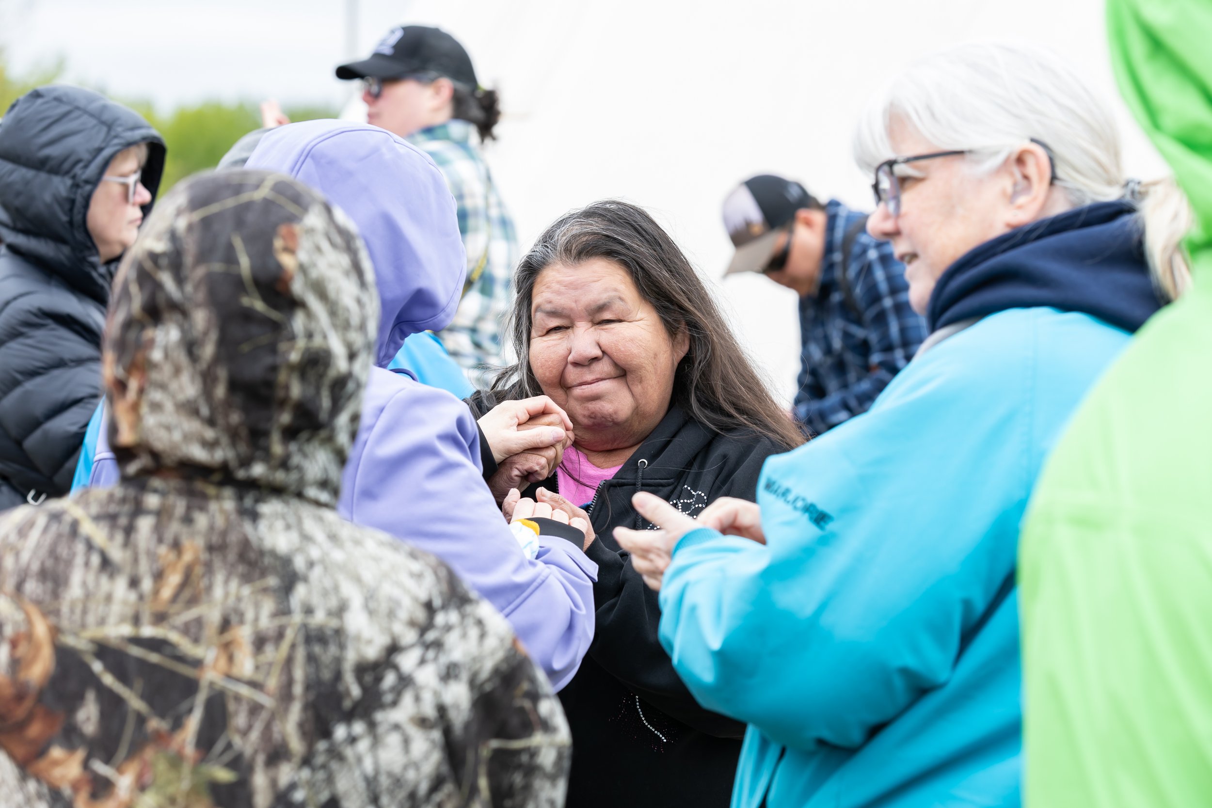 An older Indigenous woman converses with a small group of people.