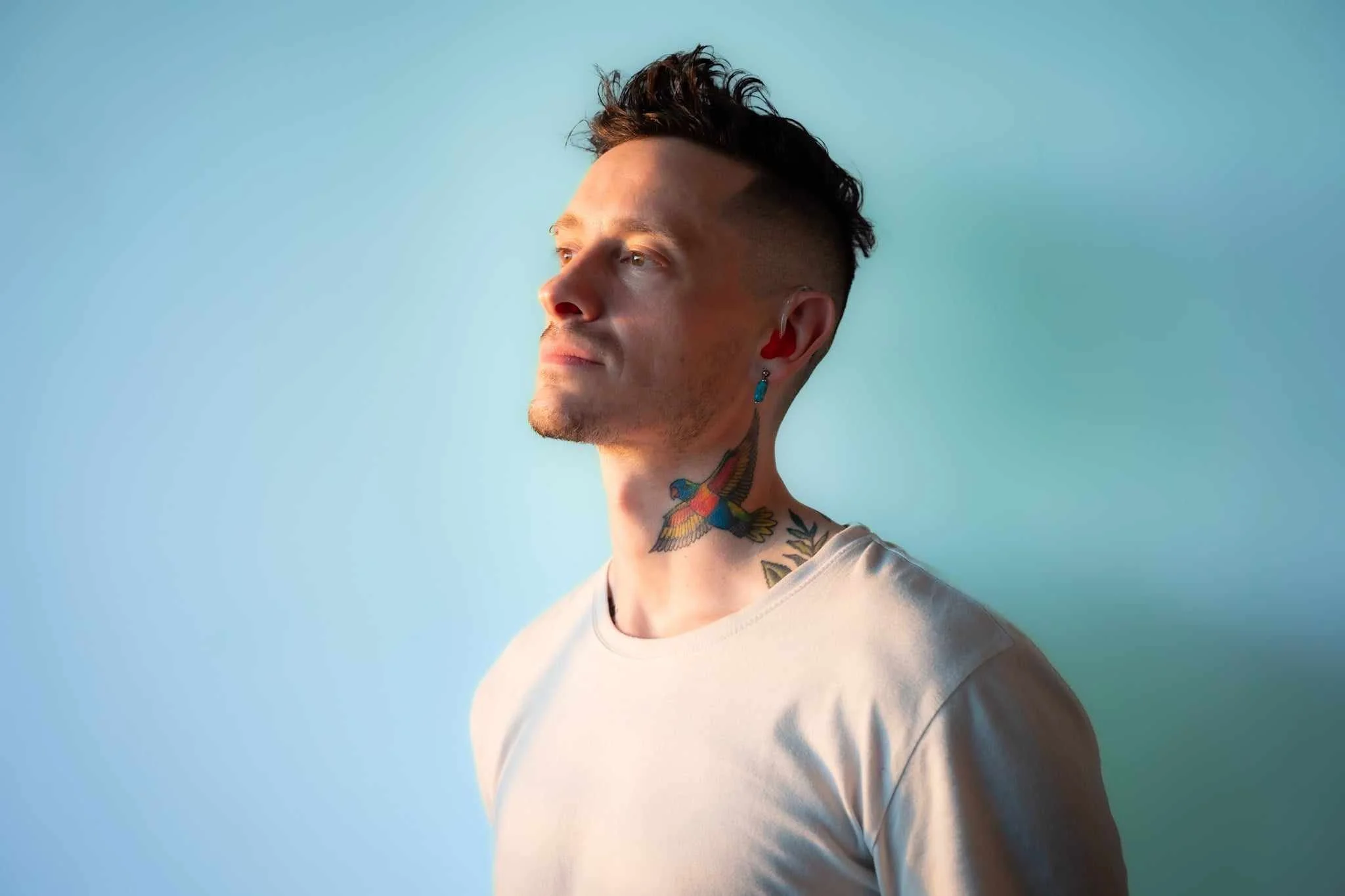 He has short stubble on his jaw and chin, and dark hair that's short and faded on the sides, with longer, textured hair swept upward on top.