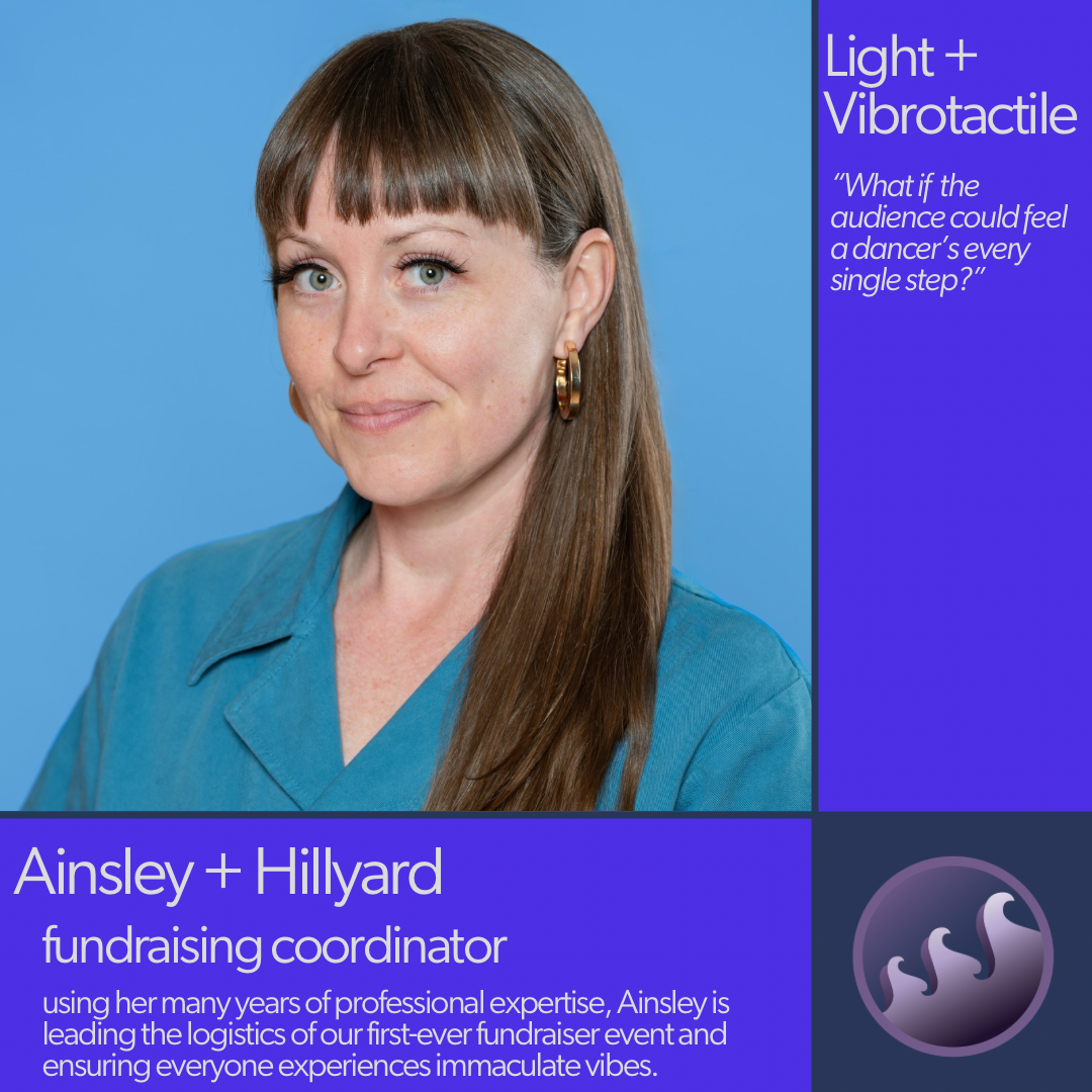 Ainsley is a middle aged white woman with blue/green eyes and long brown hair. She has blunt bangs and is wearing a blue collared shirt and gold hoop earrings.