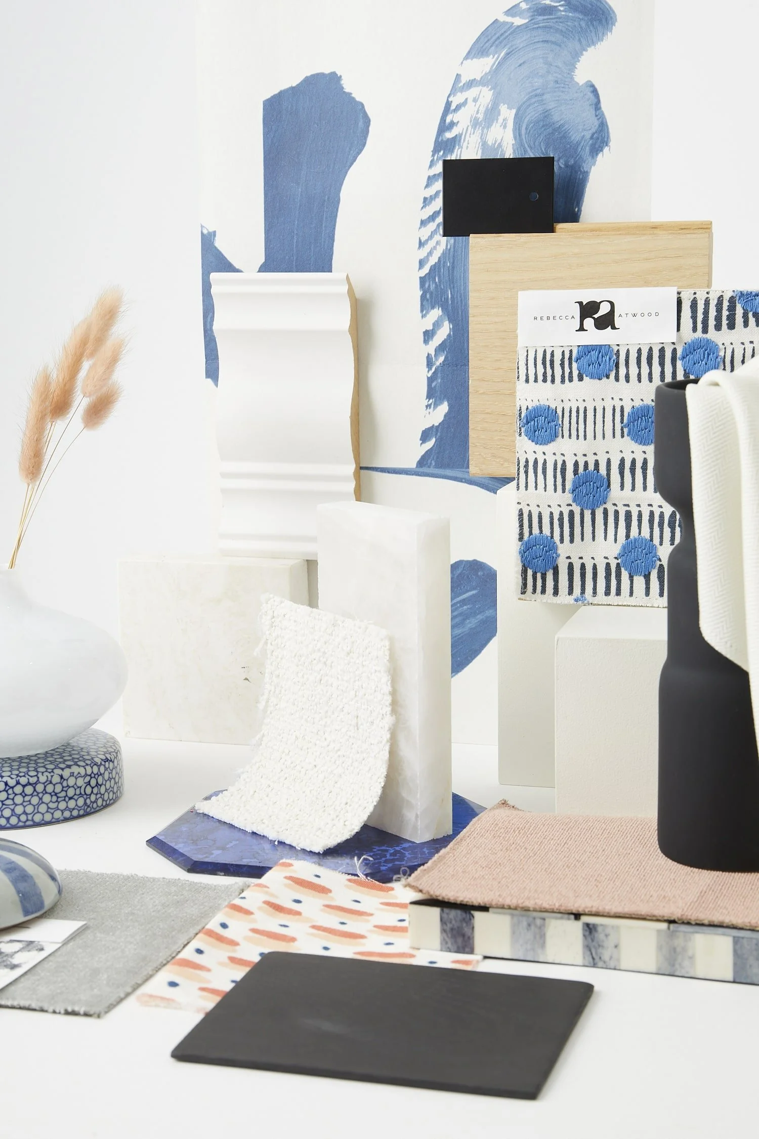 Interior display of fabric swatches, tiles, and decorative materials with a blue and white art background