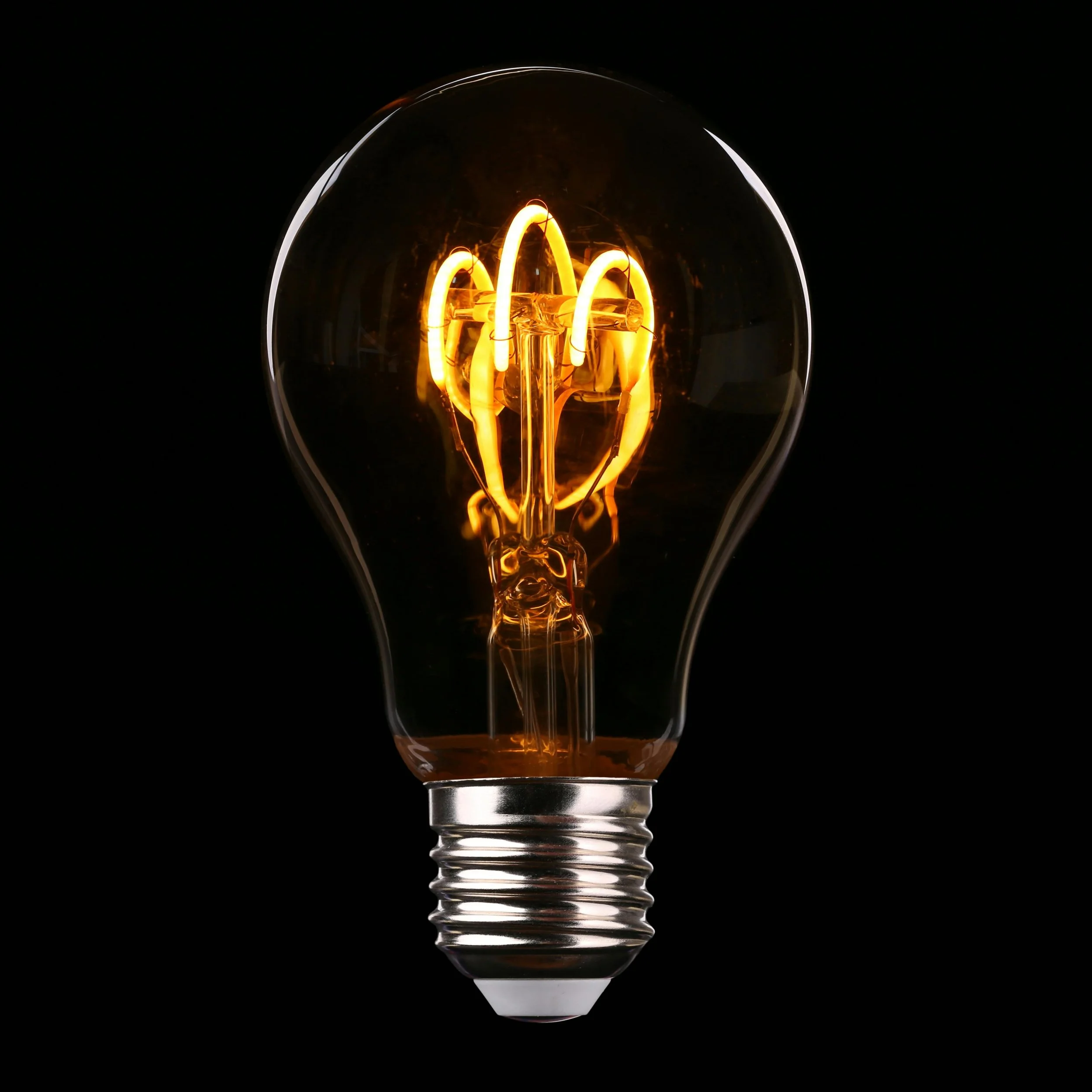 Close-up of a vintage incandescent light bulb turned on against a black background.