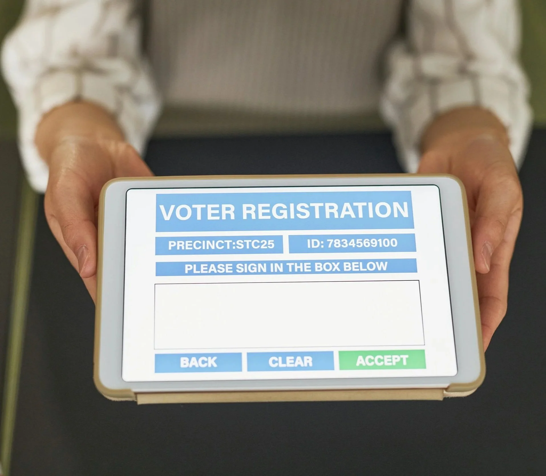 A person holding a smartphone displaying a voter registration form with a precinct number, ID, and options to sign in, clear, or accept.