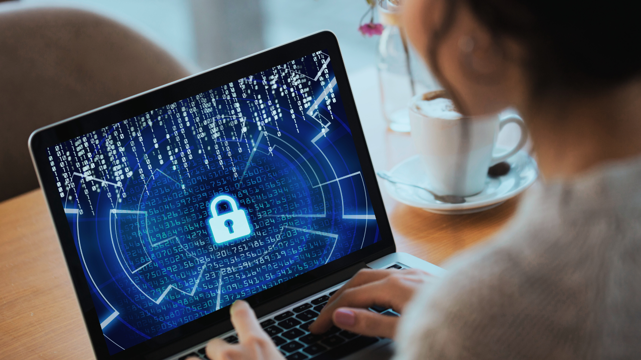 Person using a laptop with a digital security lock and binary code on the screen, indicating cybersecurity or data protection.