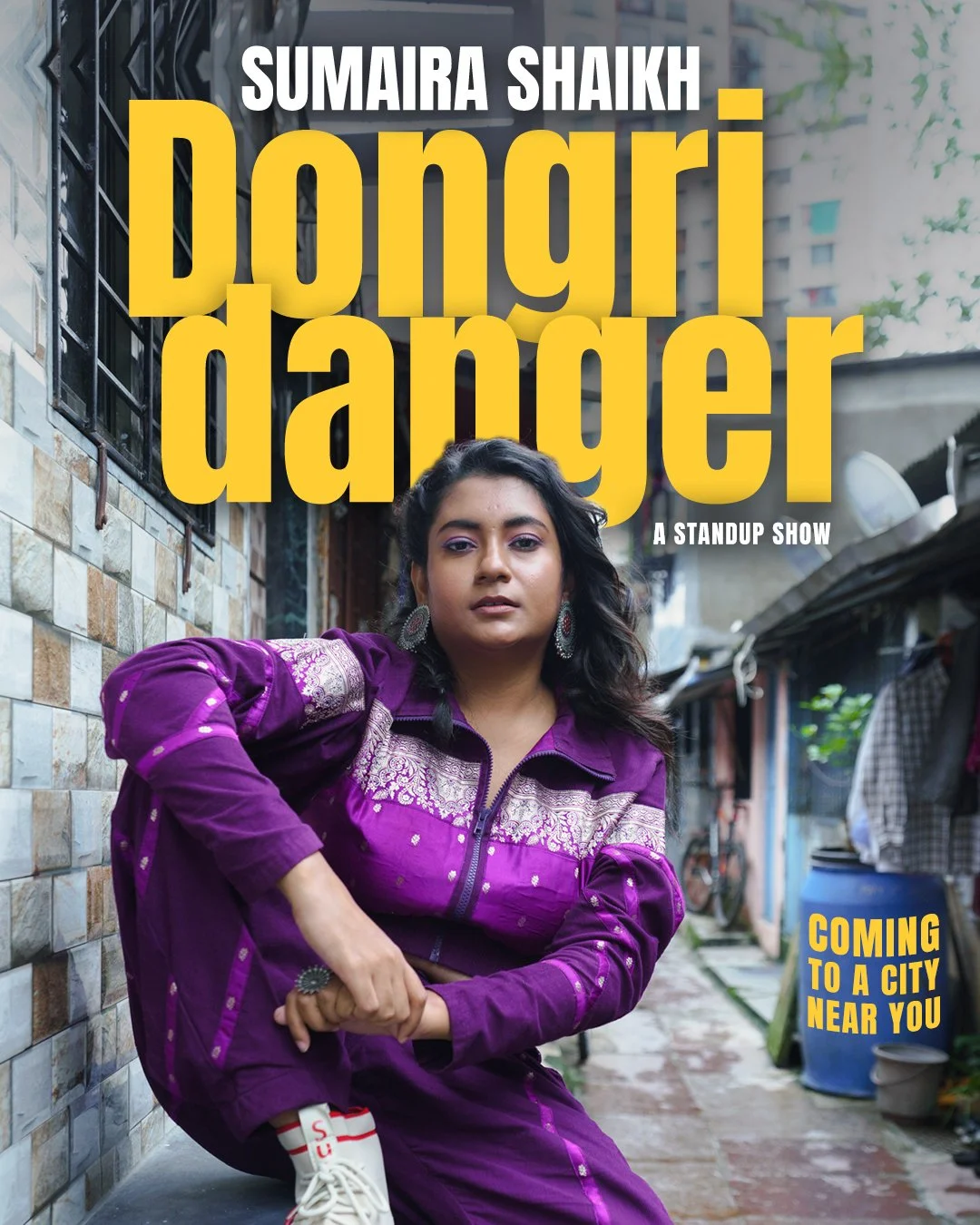 Poster of a standup show featuring a person in a vibrant purple outfit, sitting on a tiled pathway. Text reads "Sumaira Shaikh Dongri Danger A Standup Show" with "Coming to a city near you." in yellow.