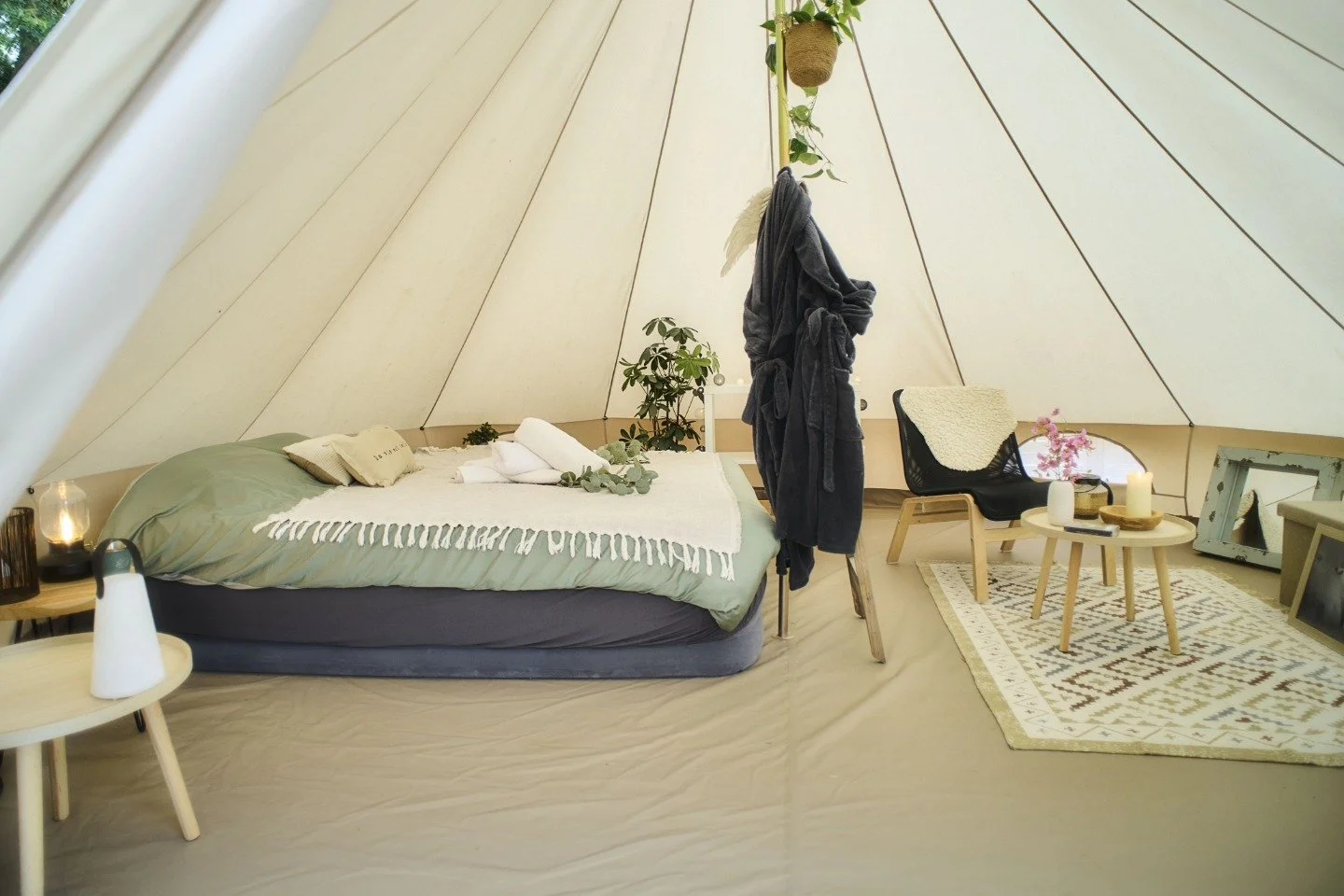 Une chambre ambiance douce et naturelle avec un lit, des tables d'appoint, un fauteuil, un tapis et des plantes.