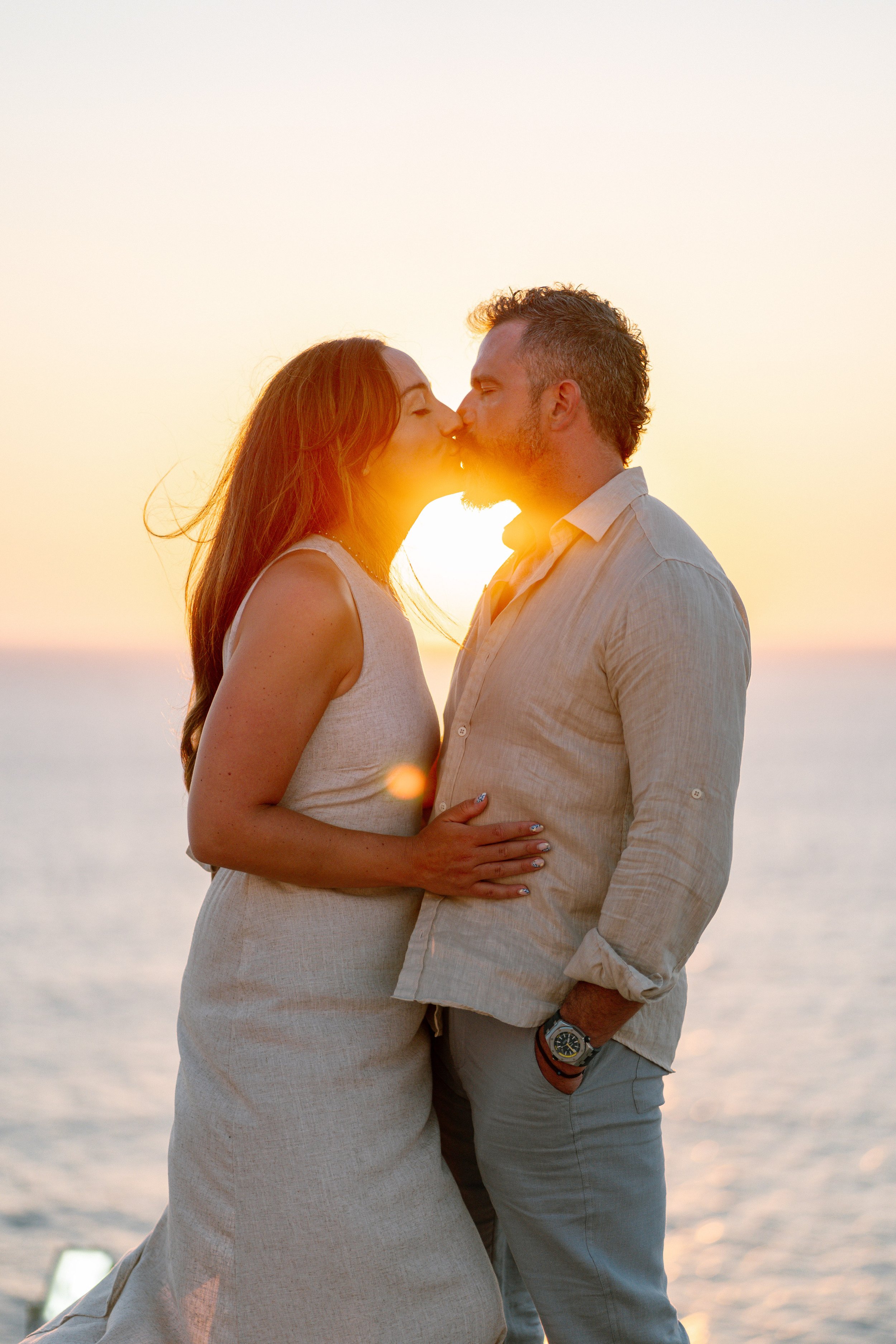 A couple sharing a kiss at sunset by the water.