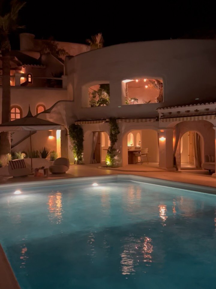 Fincadelica Xarraca by Night. 

Where soulful luxury meets Mediterranean magic.

As the sun dips, the villa transforms, warm light spills onto smooth stone, the pool glows invitingly, and shadows dance across ivy-covered walls.

Evenings here are mad
