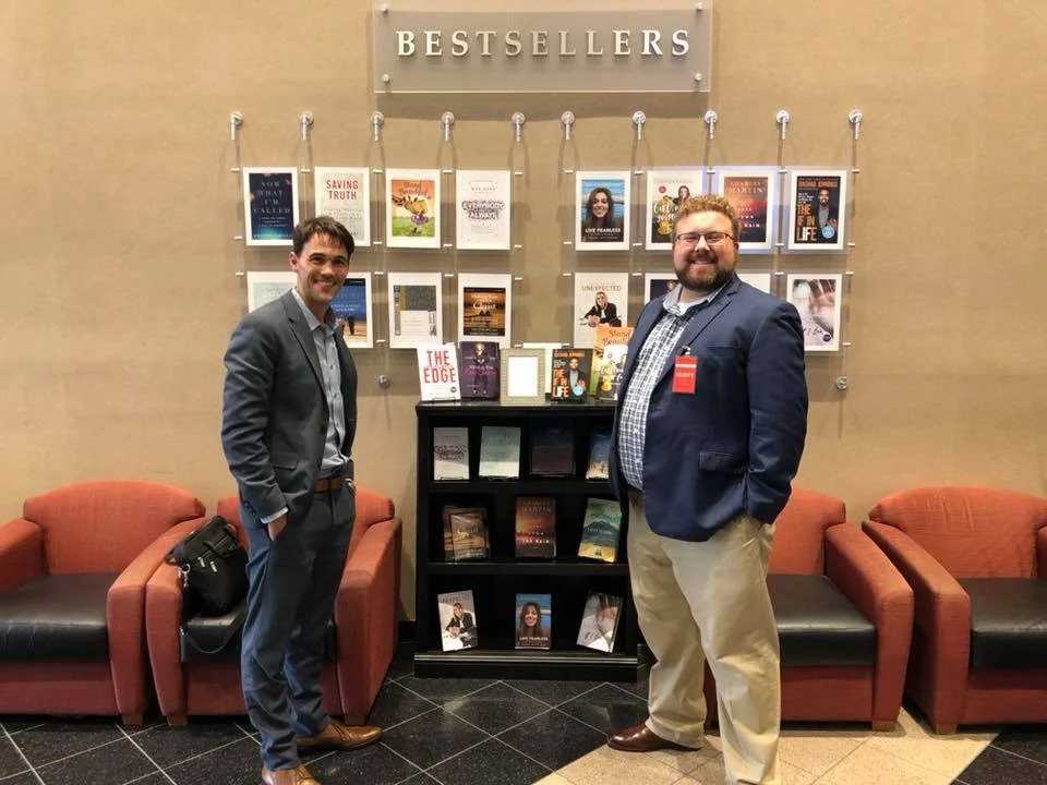 Business book ghostwriter Derek Lewis and author Matthew Pollard at HarperCollins Leadership offices, standing in front of a bestseller display featuring their collaboration, The Introvert's Edge