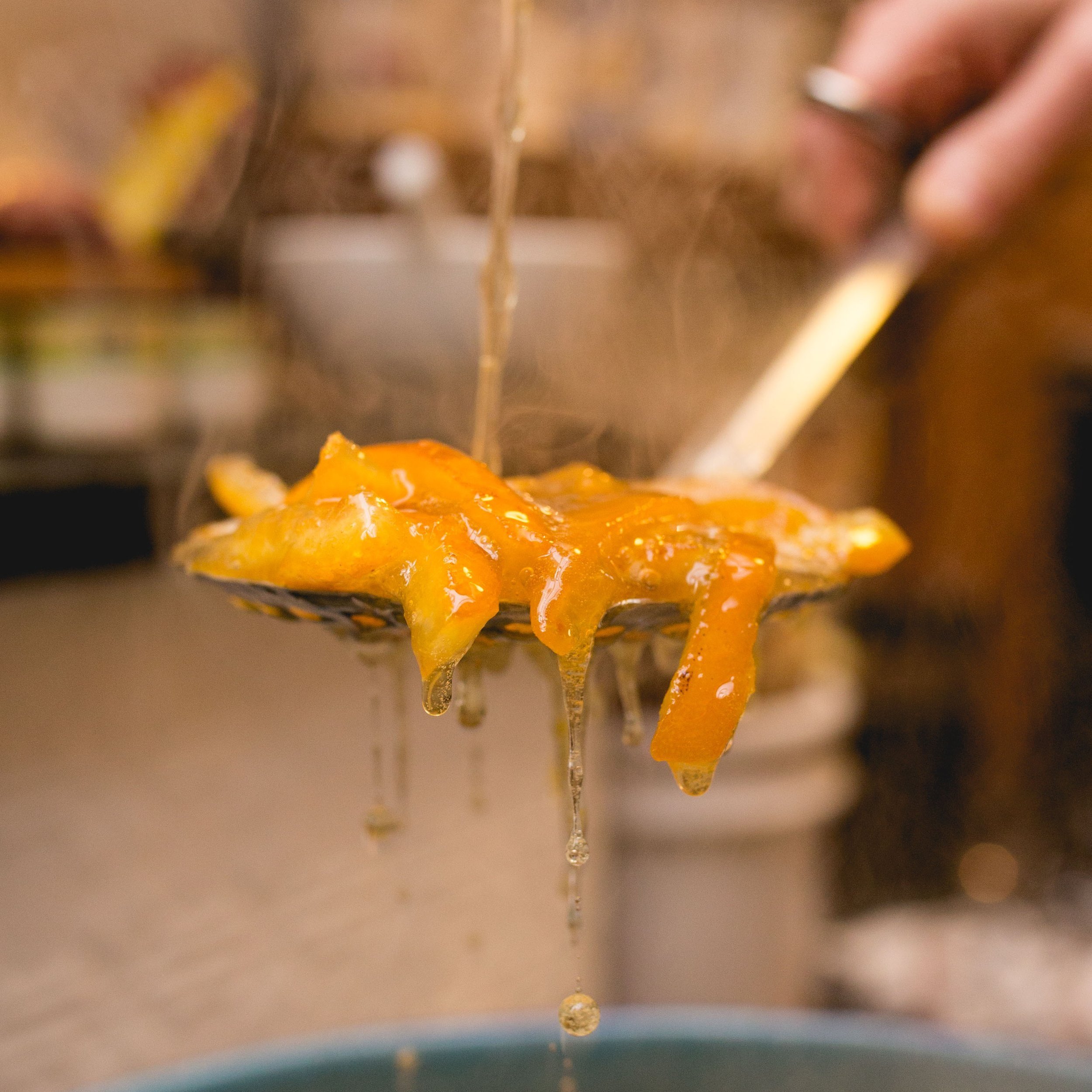 Cooked orange slices on a slotted spoon over a steaming pot