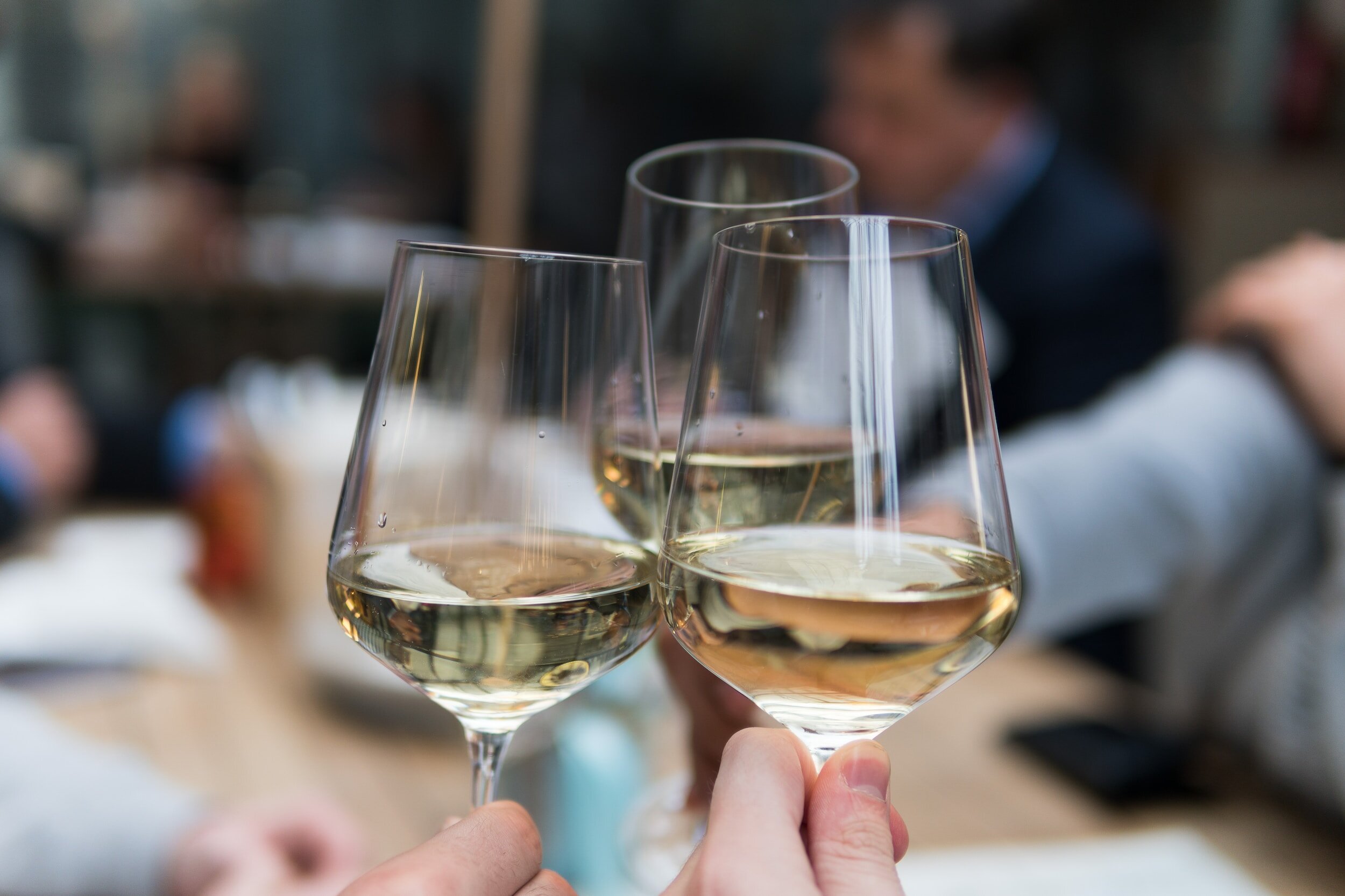 Three hands toasting with glasses of wine