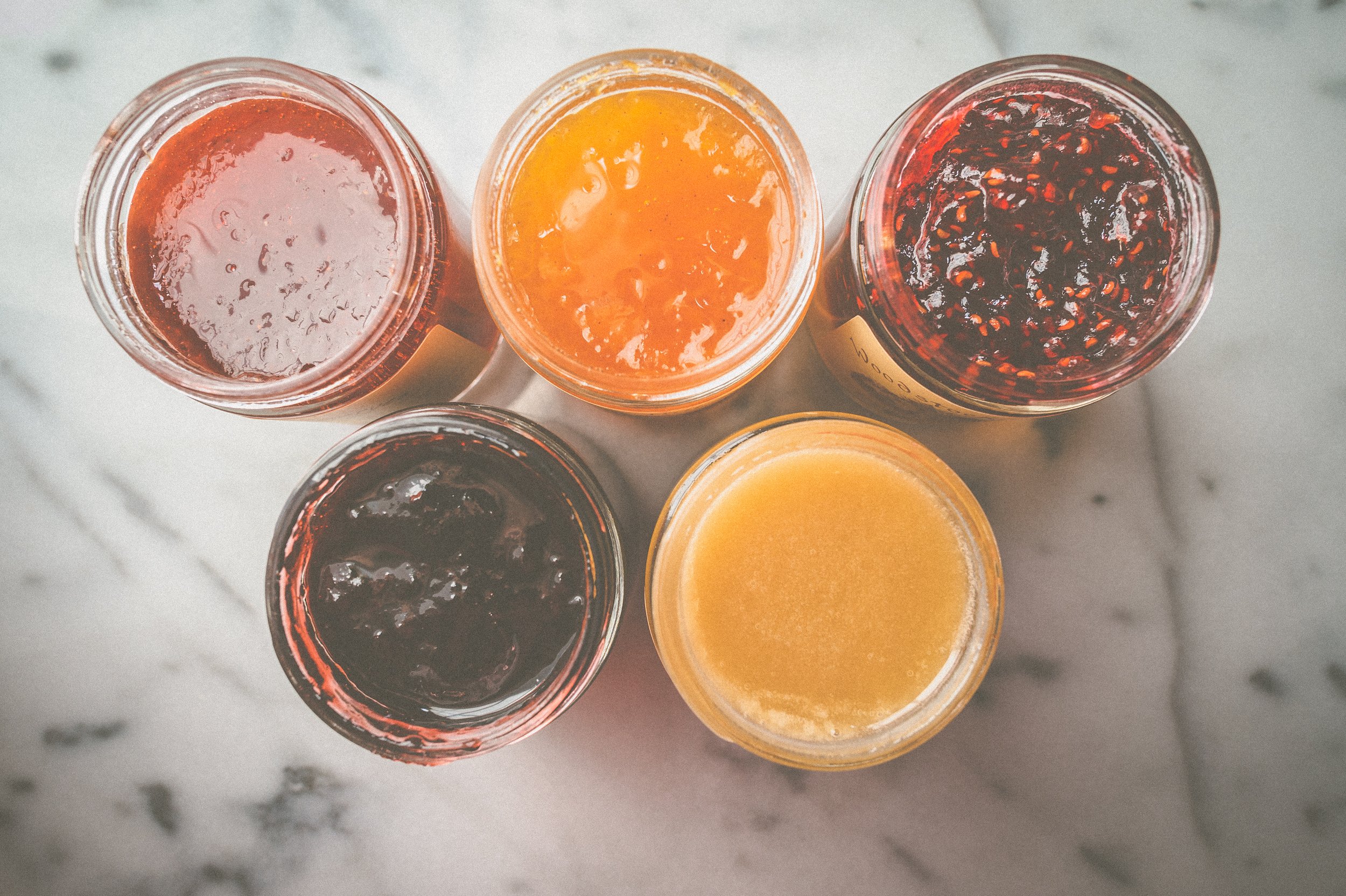 5 jars of different flavored jams photographed from above