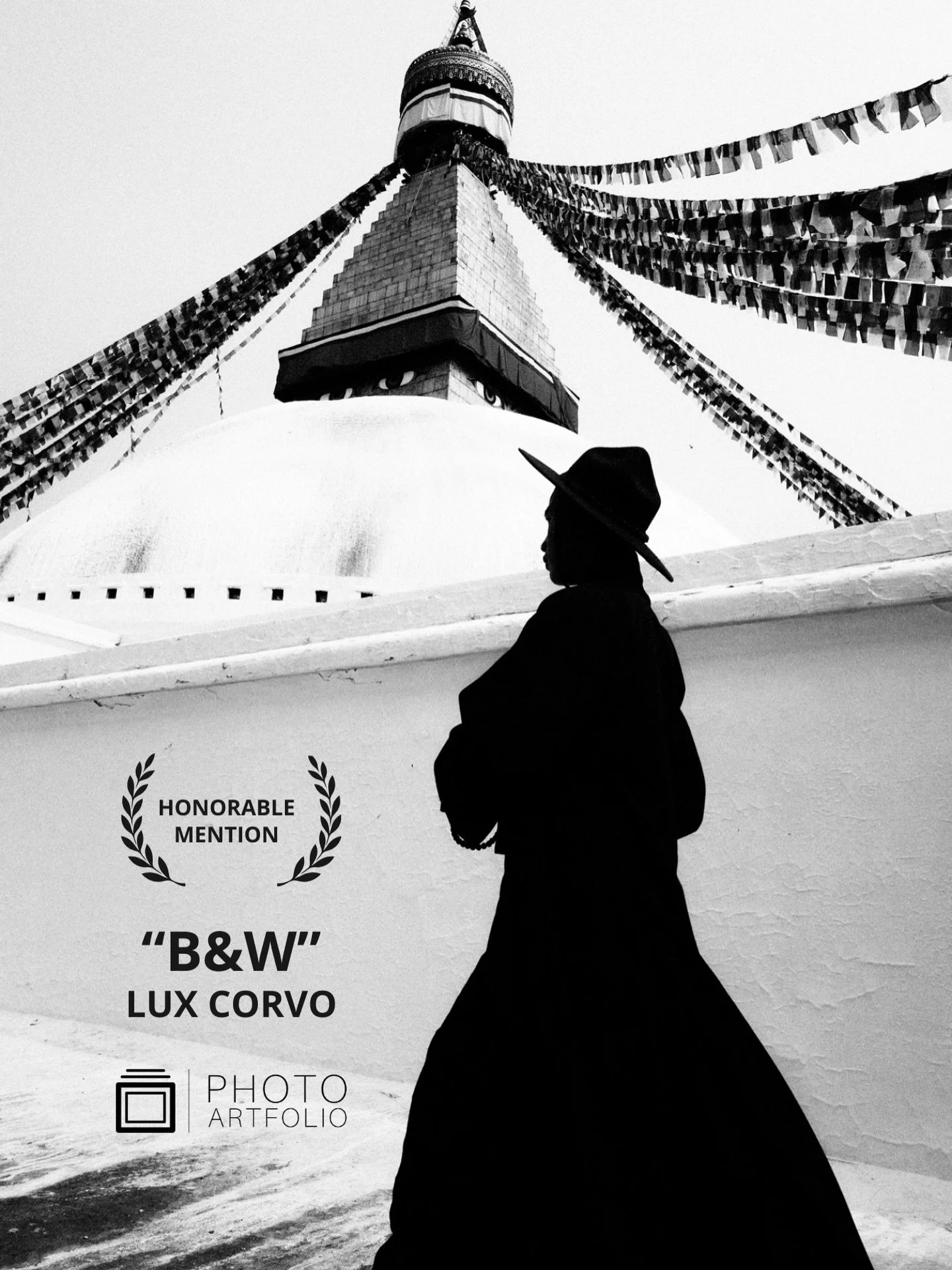 📷 B&amp;W: The Poetry of Light &amp; Shadow
Honorable Mention
&ldquo;Passing&rdquo; by Lux Corvo (@luxcorvo)

A solitary figure moves through shadow as form and faith rise above. The architecture stands still while the body passes &mdash; a brief ge