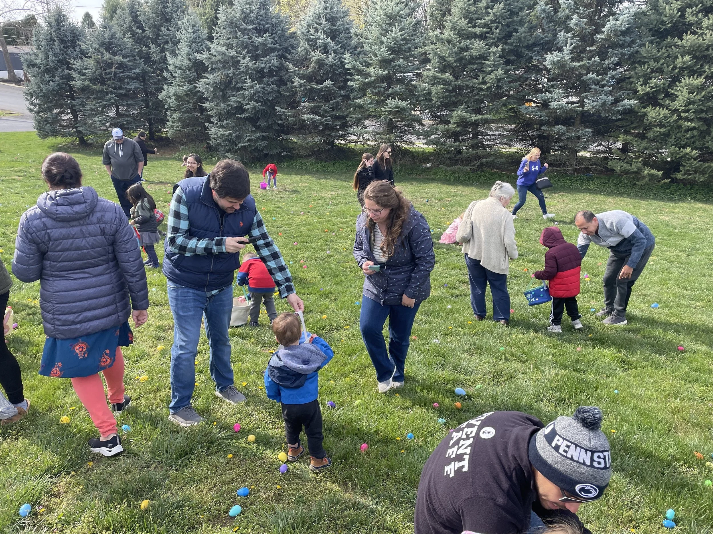 A group of children and parents searching for Easter eggs in the grass