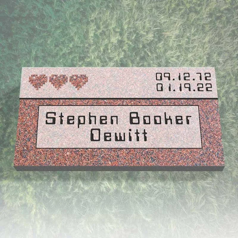 A gravestone with the name Stephen Booker Dewitt, decorated with three heart decals, and engraved with birth date December 9, 1972, and death date January 19, 2022, lying on grass.