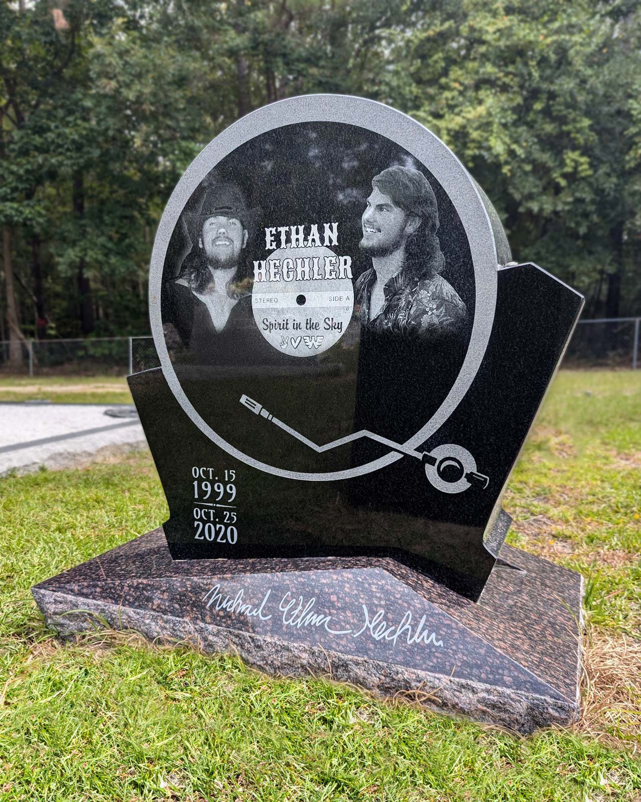 A memorial headstone for Ethan Hegler with images of him on a record, dates October 15, 1999, to October 25, 2020, and a musical design. The headstone is outdoors on a grassy area surrounded by trees.