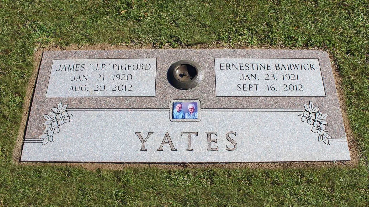 Gravestone with the surname Yates, two side-by-side plaques with names James J.P. Pigford and Ernestine Barwick, dates of birth and death, a small framed photograph of an elderly couple, floral engravings, and a small hole for a flower or candle.