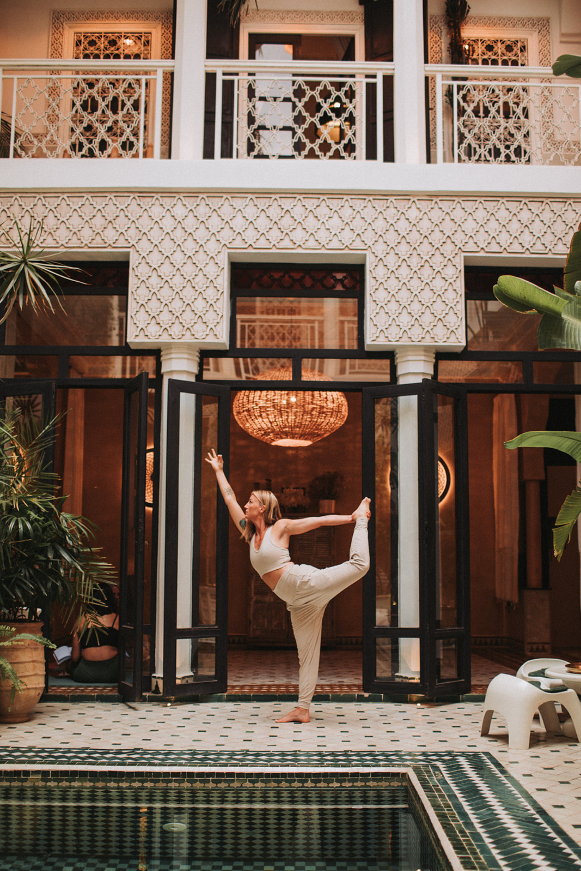 Woman practicing yoga dancer pose in a beautiful courtyard at a wellness retreat venue, showcasing mindful movement and retreat travel