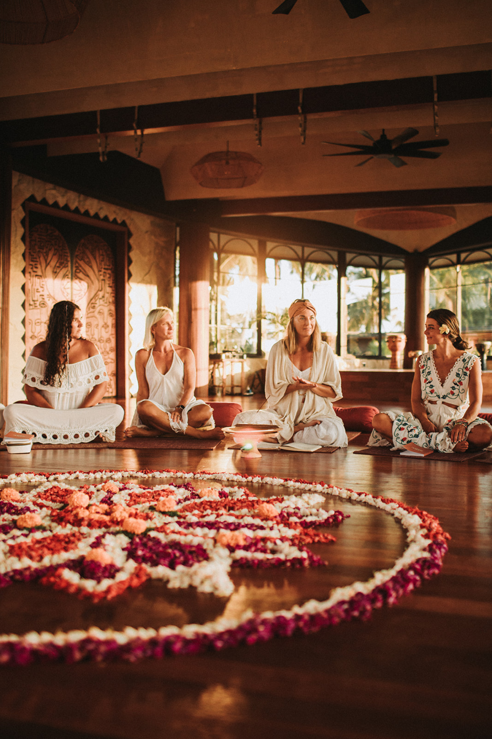 Women’s yoga retreat opening circle with flower mandala ceremony indoors at Flow State Wellness.