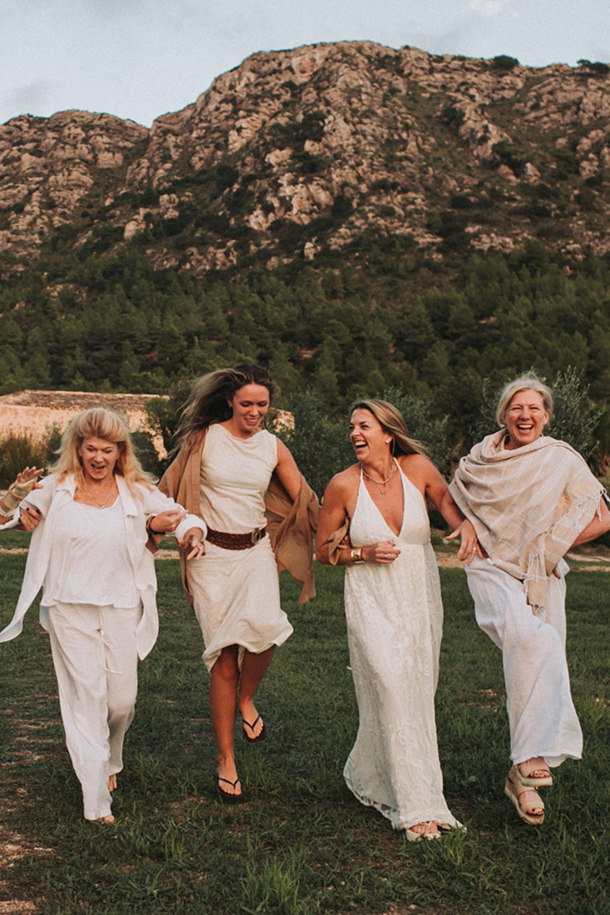 Women laughing and walking together at a wellness retreat with mountains in the background.