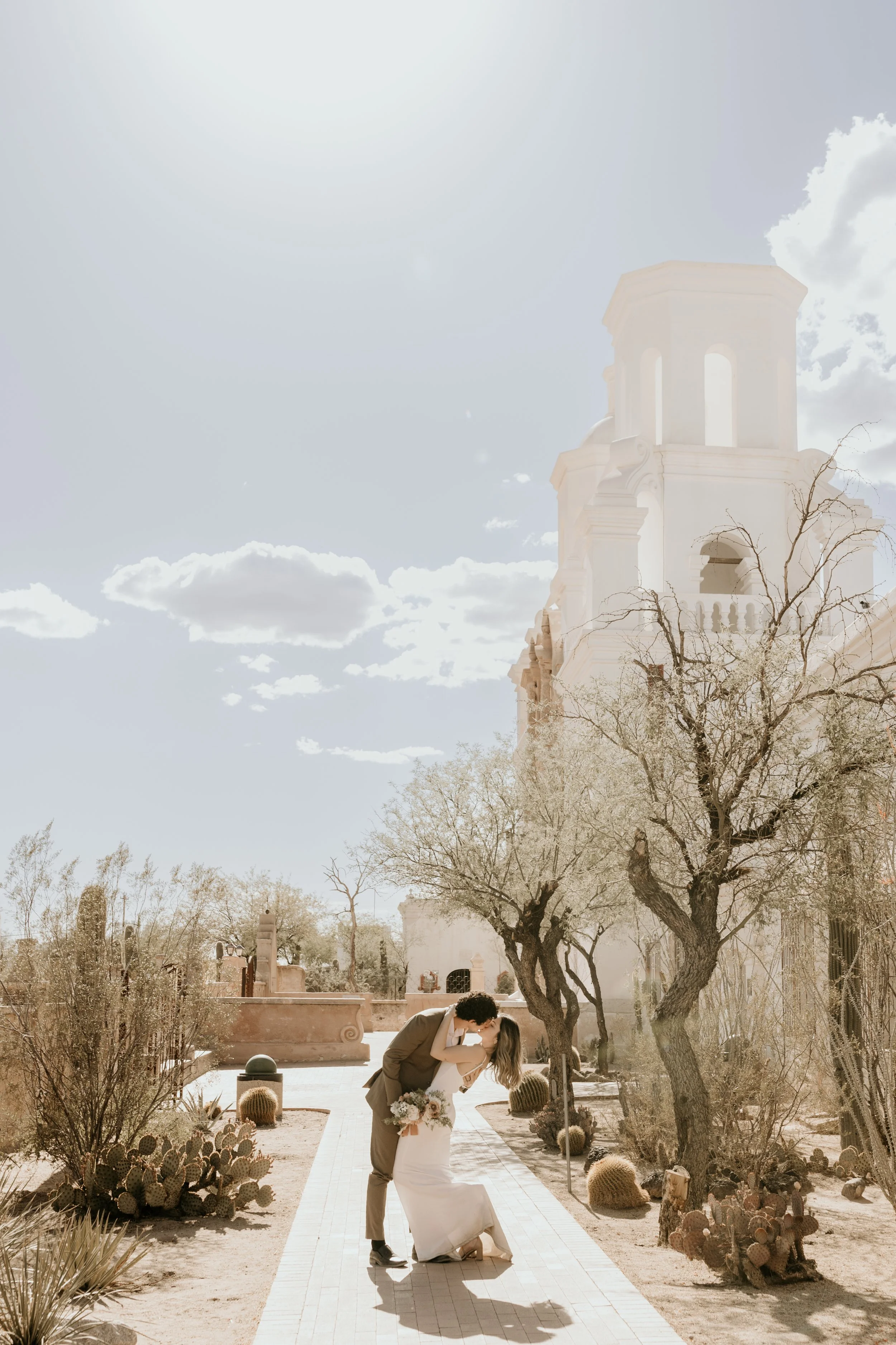A bride and groom holding hands on a beach, with the ocean in the background, during their wedding.