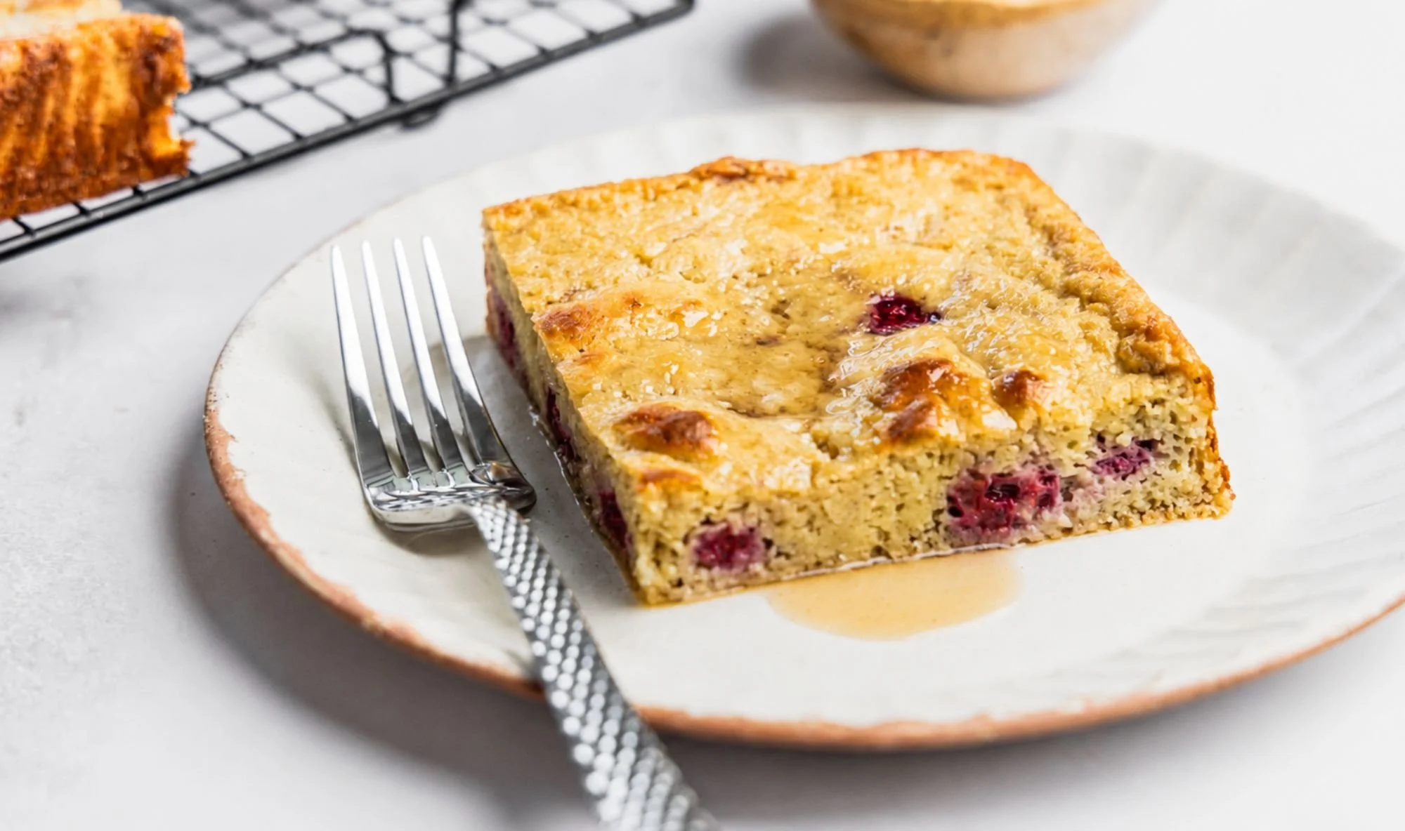 Close up of baked raspberry pancakes in a white plate with a fork