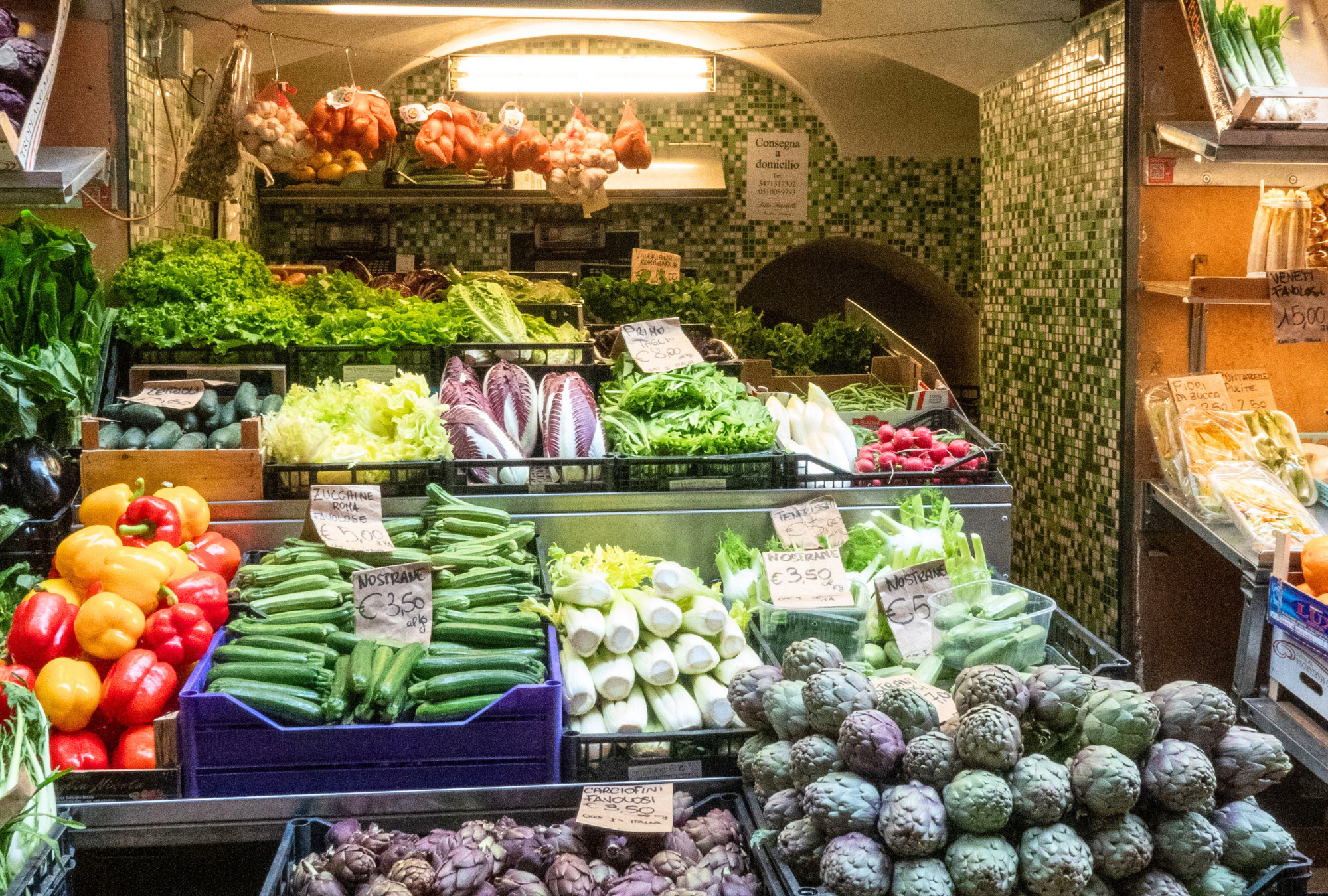 Fresh produce market stall in Italy with vegetables and hanging garlic