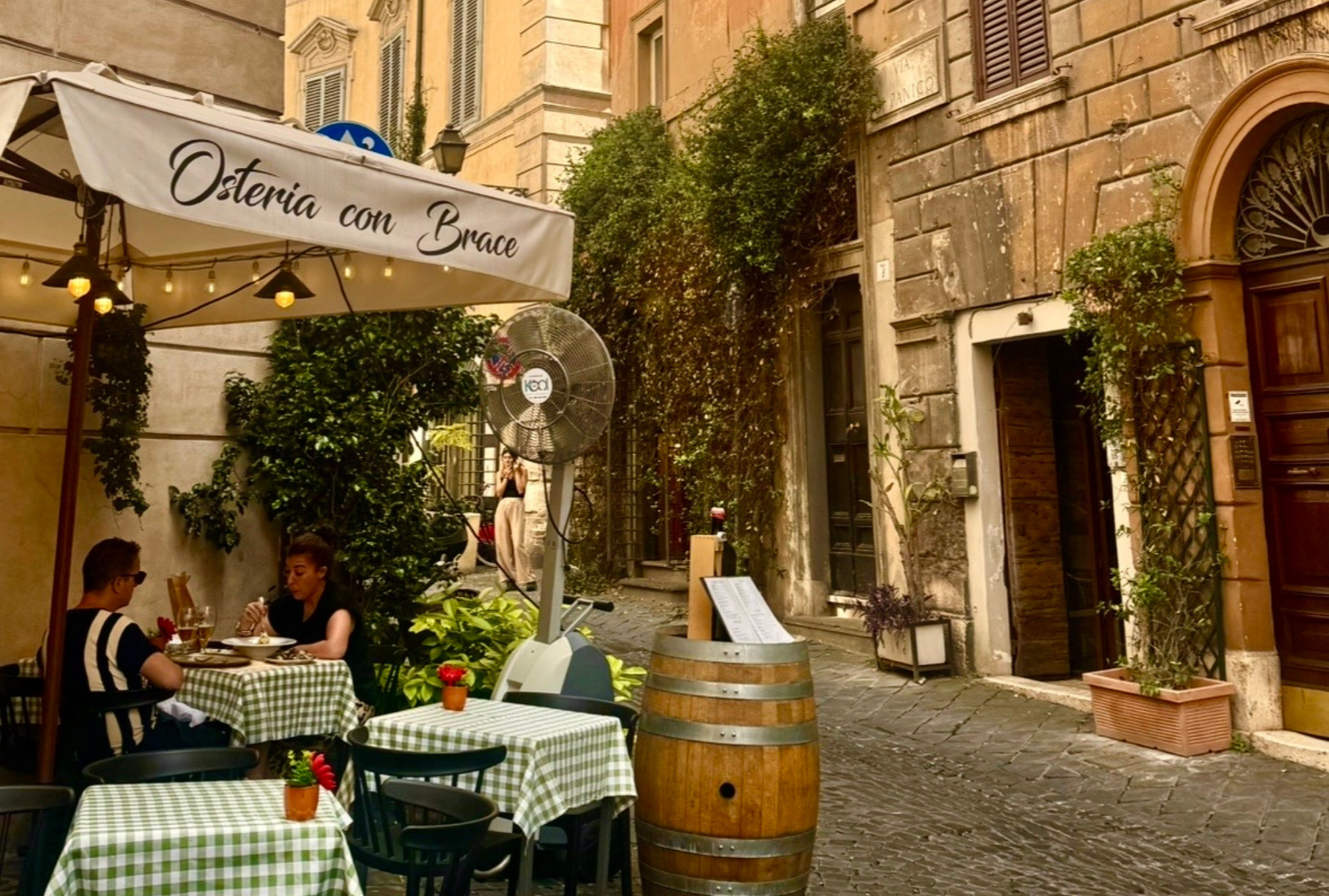 Couple dining at an outdoor restaurant table in a Roman laneway