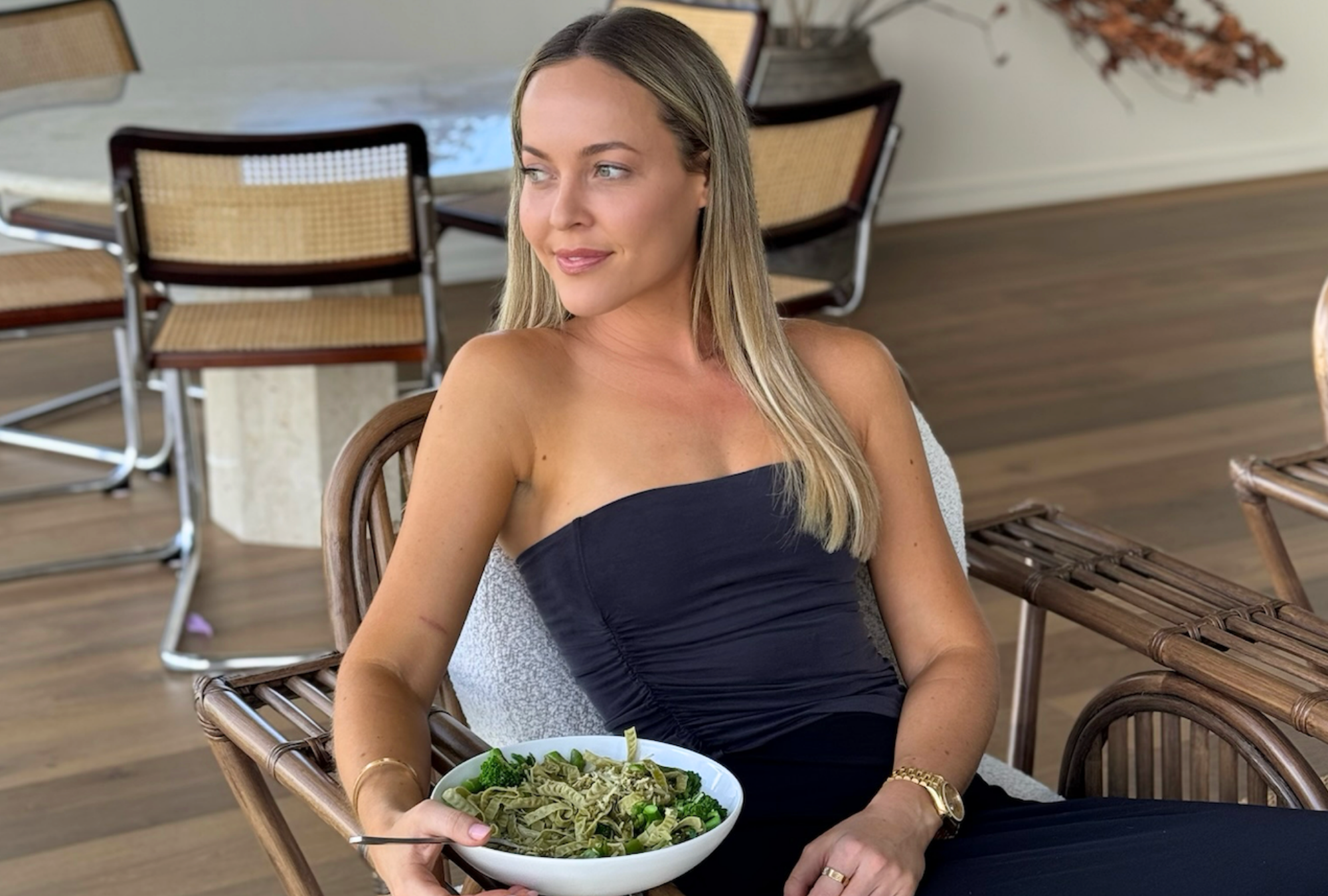 Bec sitting at home with a bowl of pasta and greens