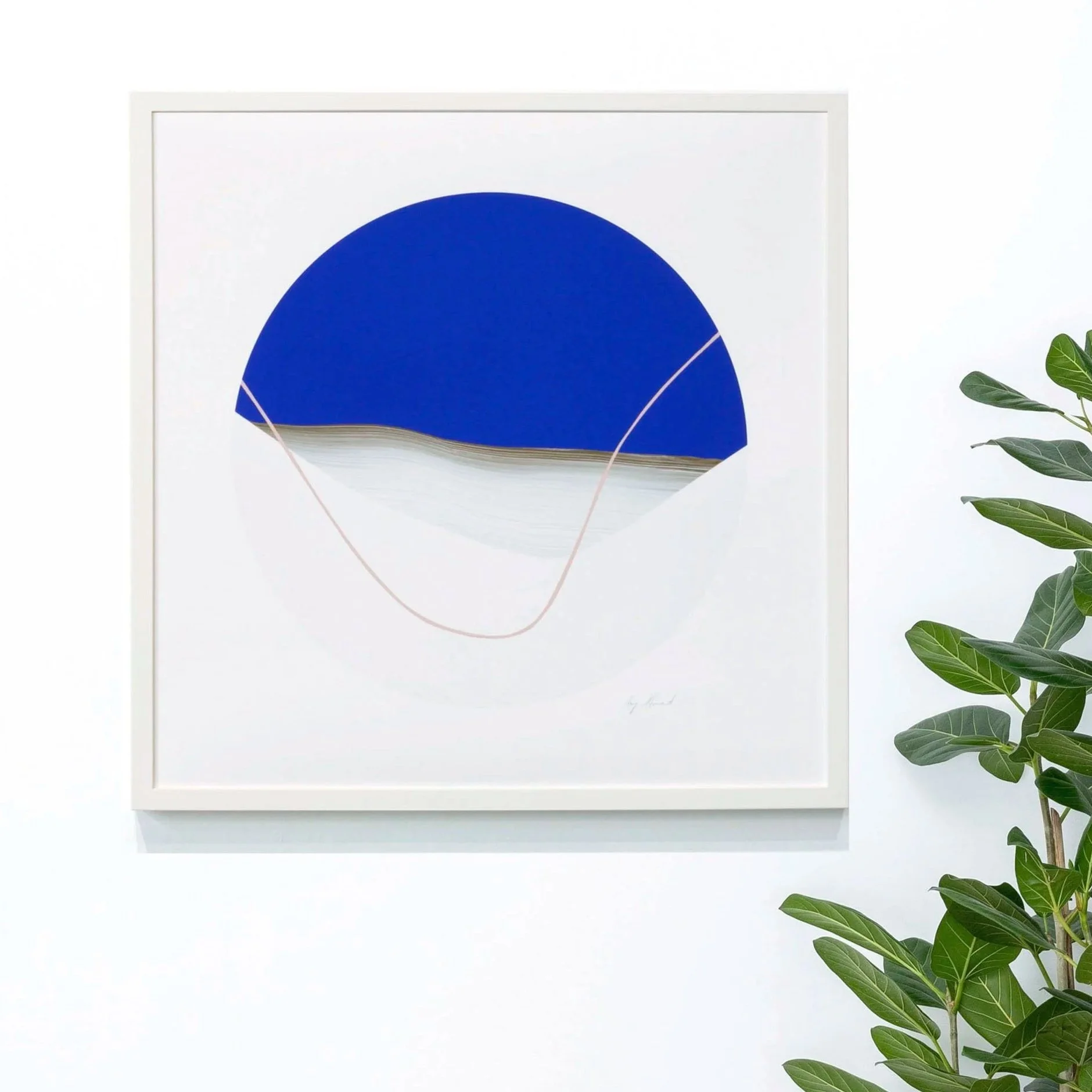 Abstract art featuring a blue semi-circle with white lines and details, framed and hanging on a white wall with green houseplant to the right.